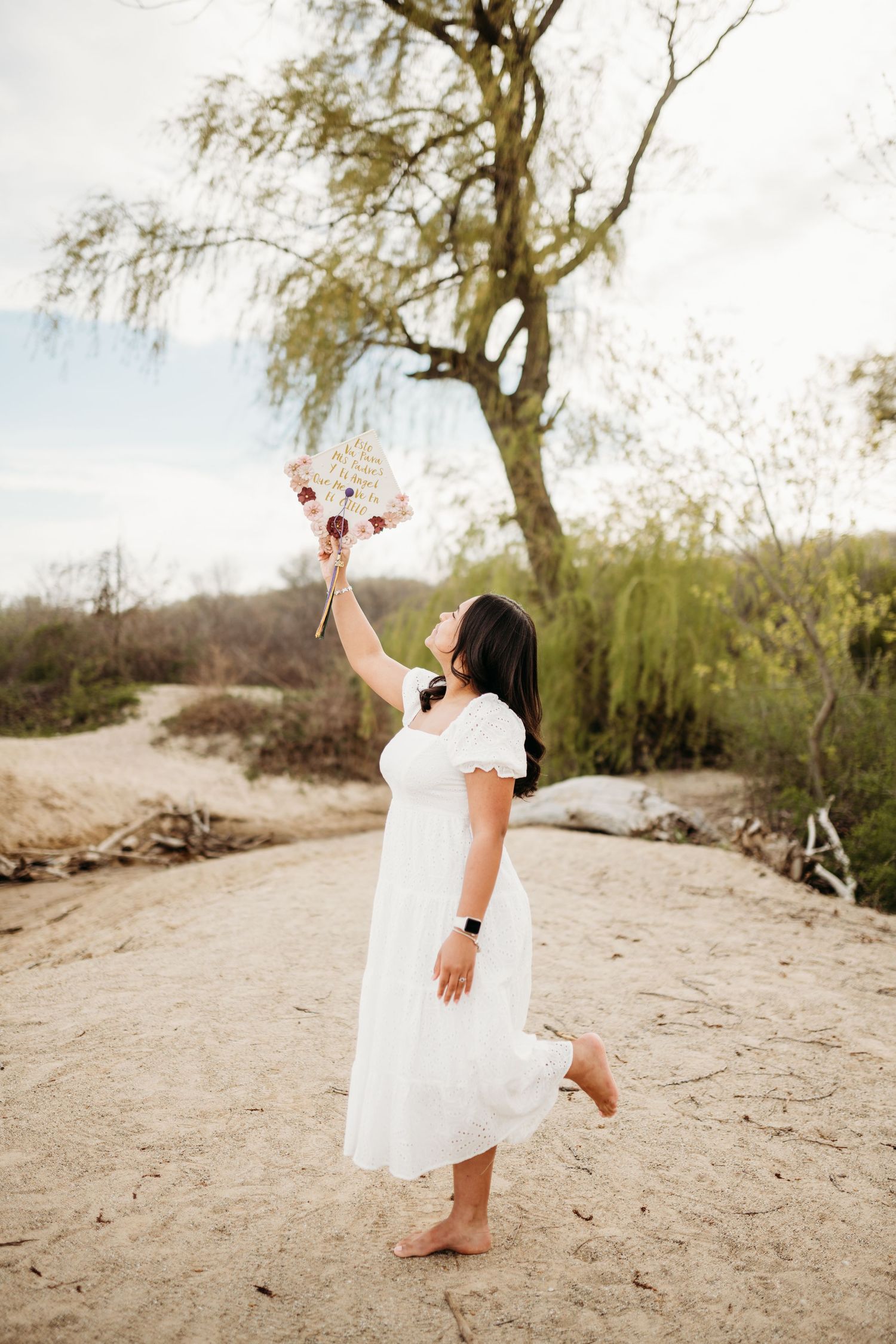 Dancing and twirling on a sandy beach in a flowing white dress.