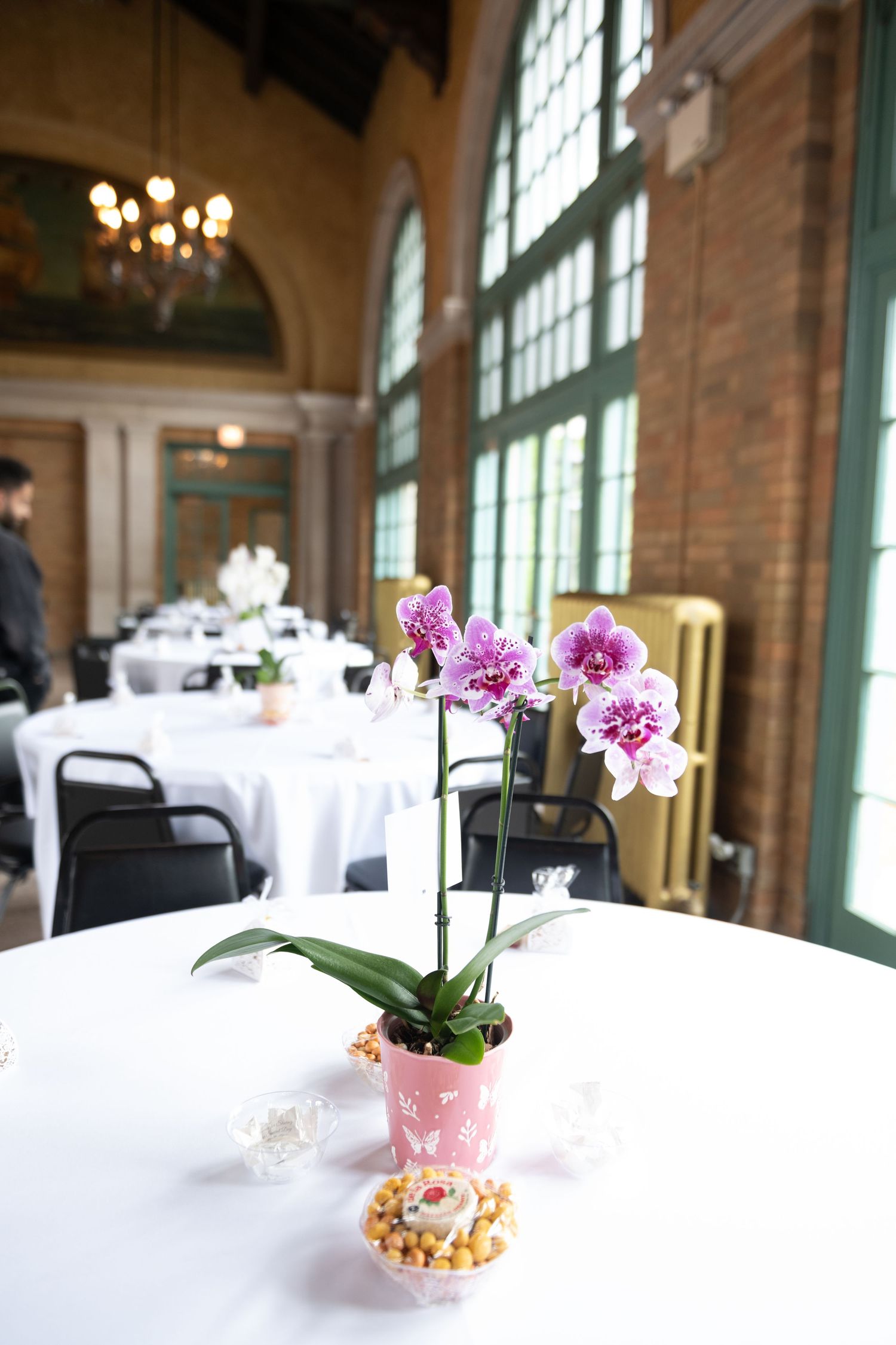 Elegant wedding reception venue with white tablecloths and delicate pink orchid centerpieces.