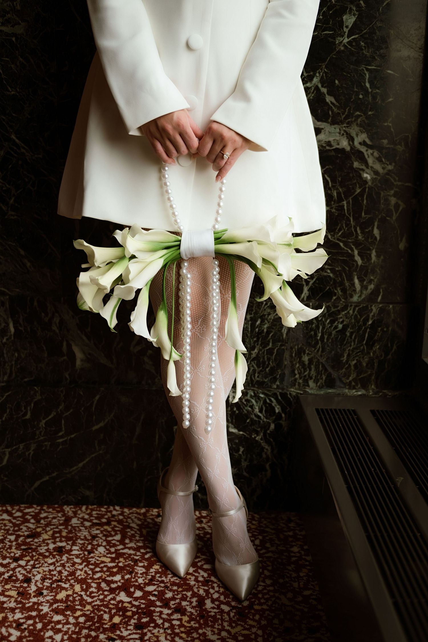 Close-up view of white wedding dress details with calla lily bouquet and elegant white boots with pearl buttons.