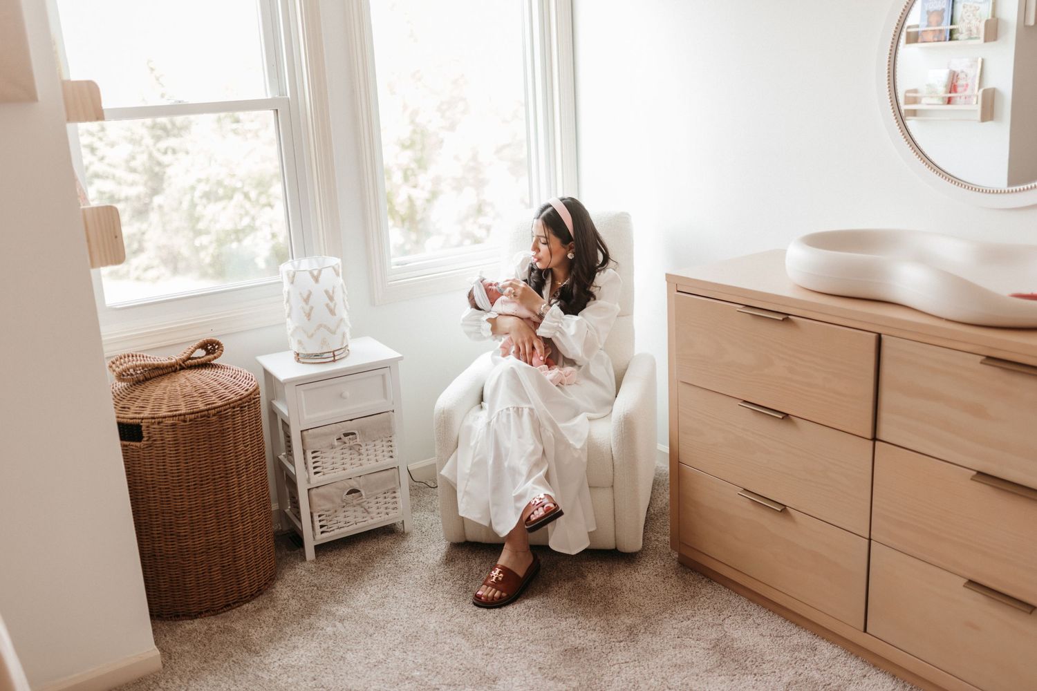 Modern nursery interior with white furniture and natural light streaming through windows.