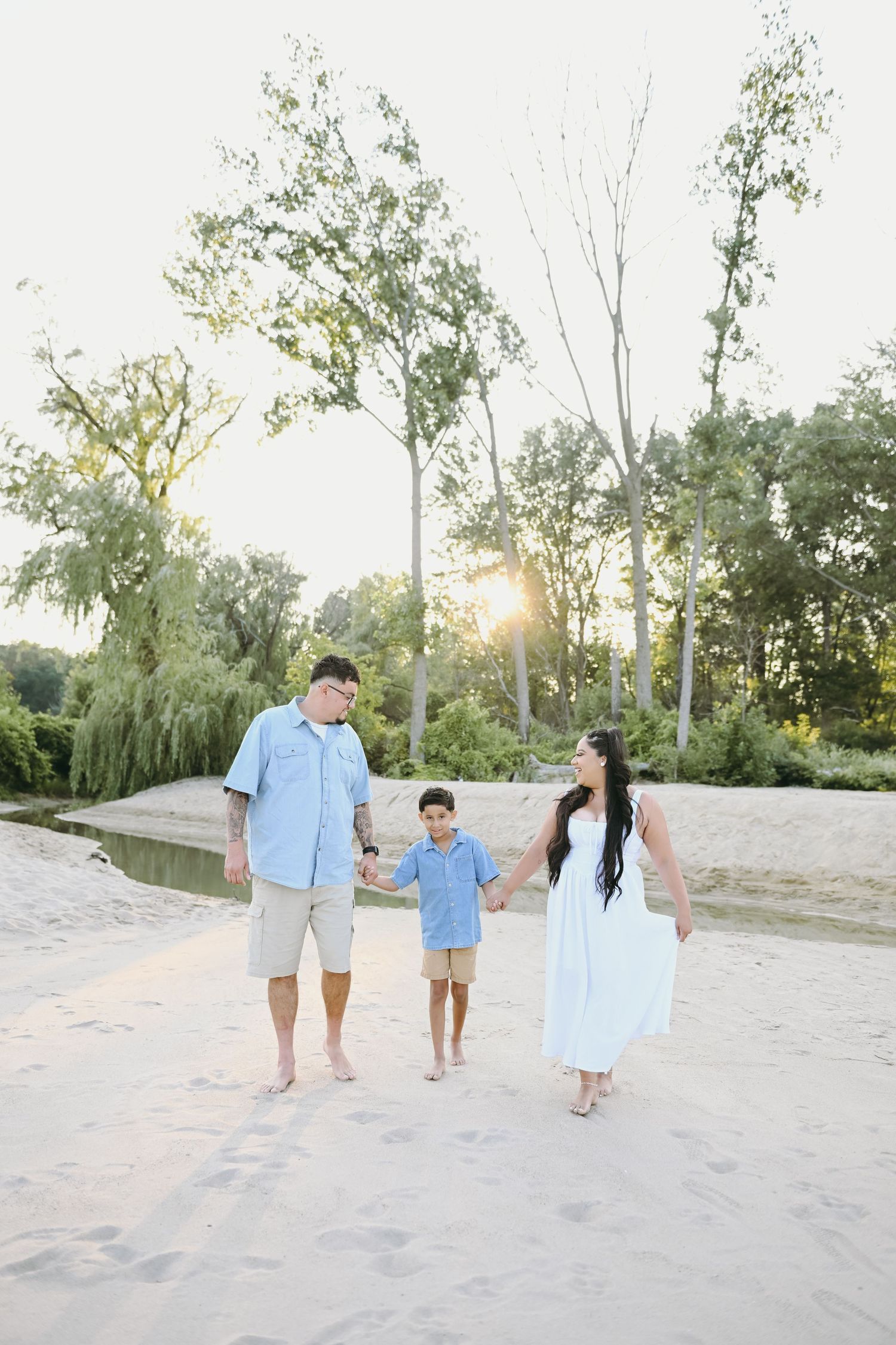 Family walking together on a sandy beach path at sunset.