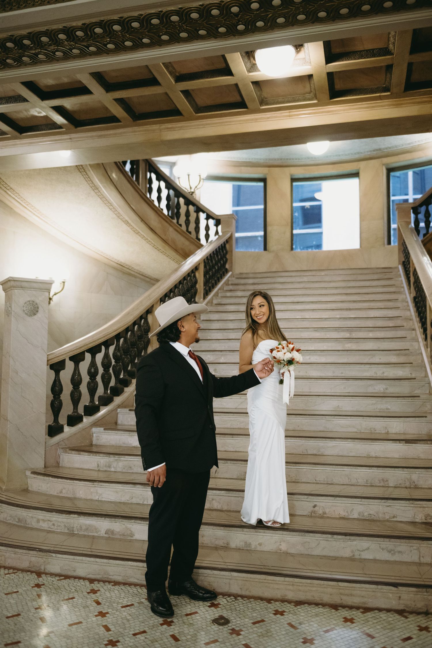 A couple dances on marble stairs in a historic building interior.