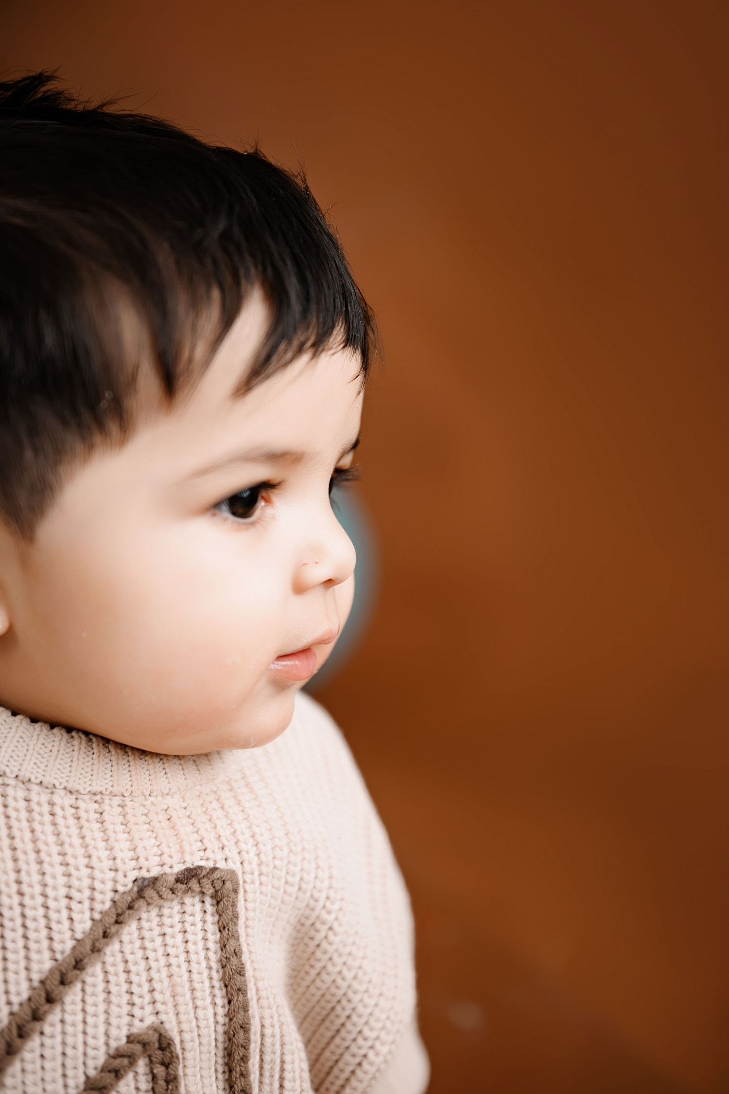 A series of close-up photos showing a doll wearing a white knit sweater against a brown background.