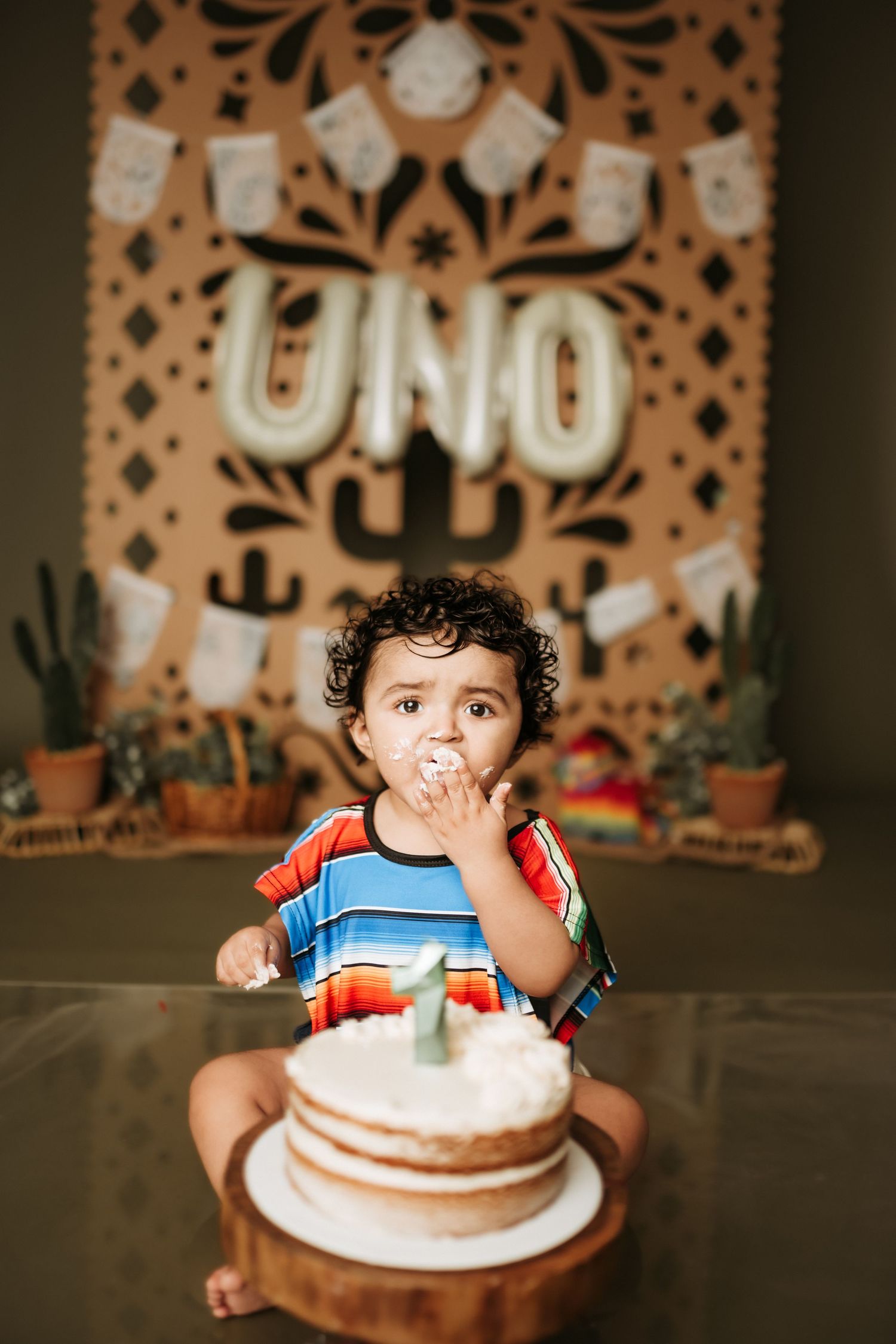 Birthday cake smash session with decorative papel picado backdrop and cactus decor.