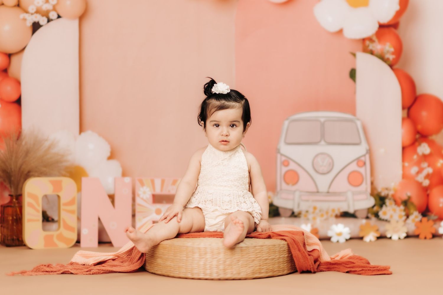 Baby photography session with peach backdrop and floral decorations.