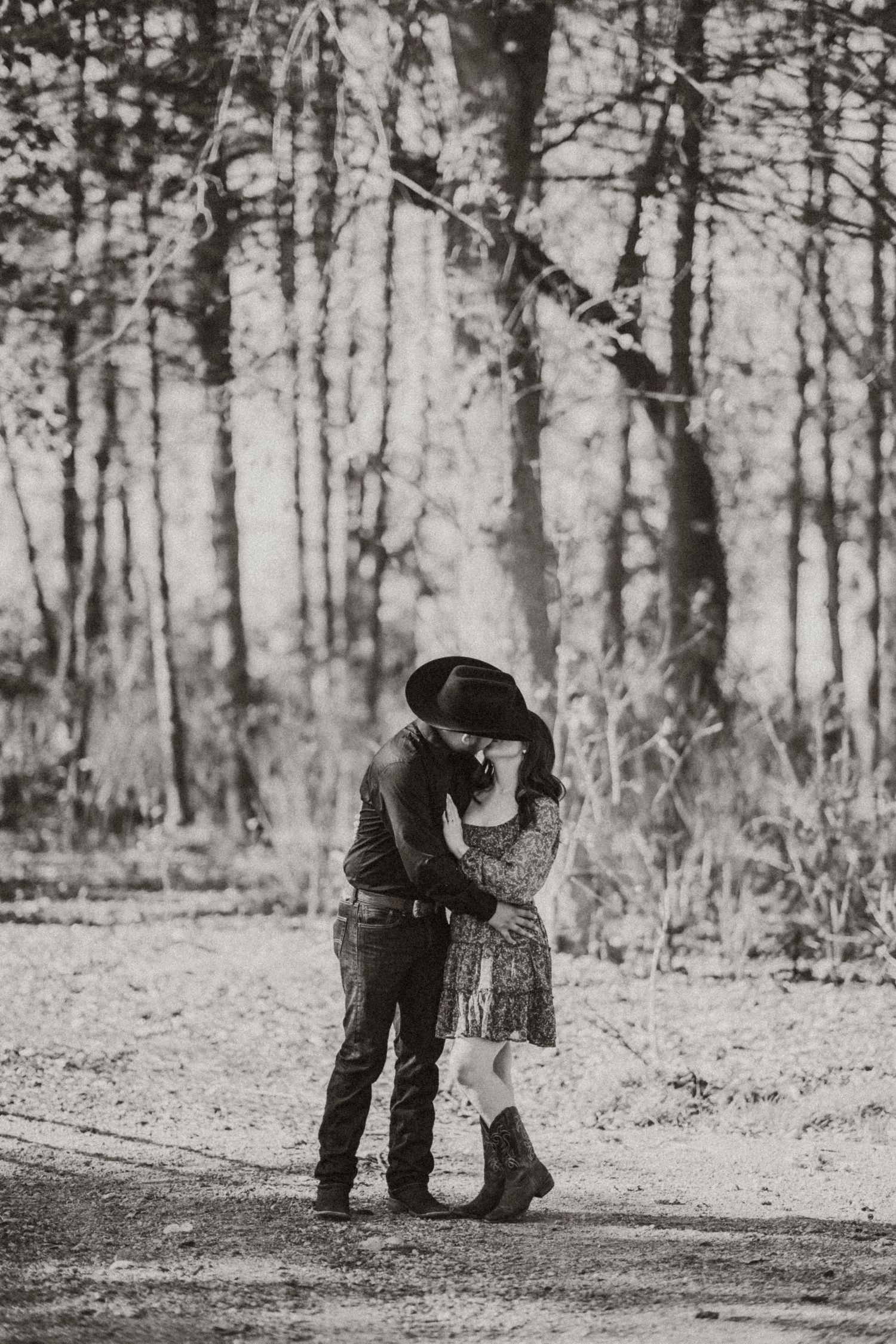 Black and white photos of a couple sharing intimate moments in a snowy forest setting.