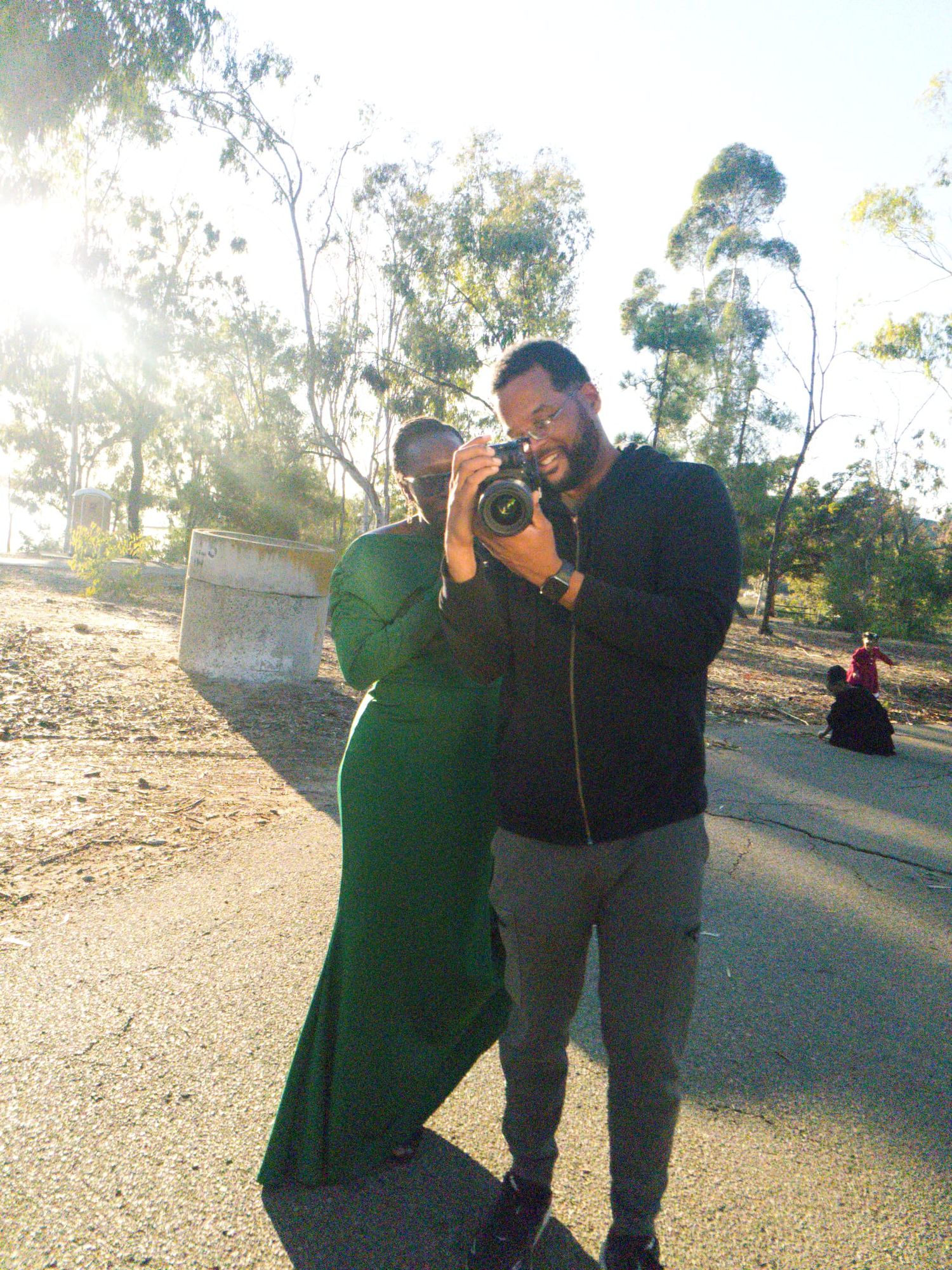 Couple in casual attire laughing together outdoors during golden hour.
