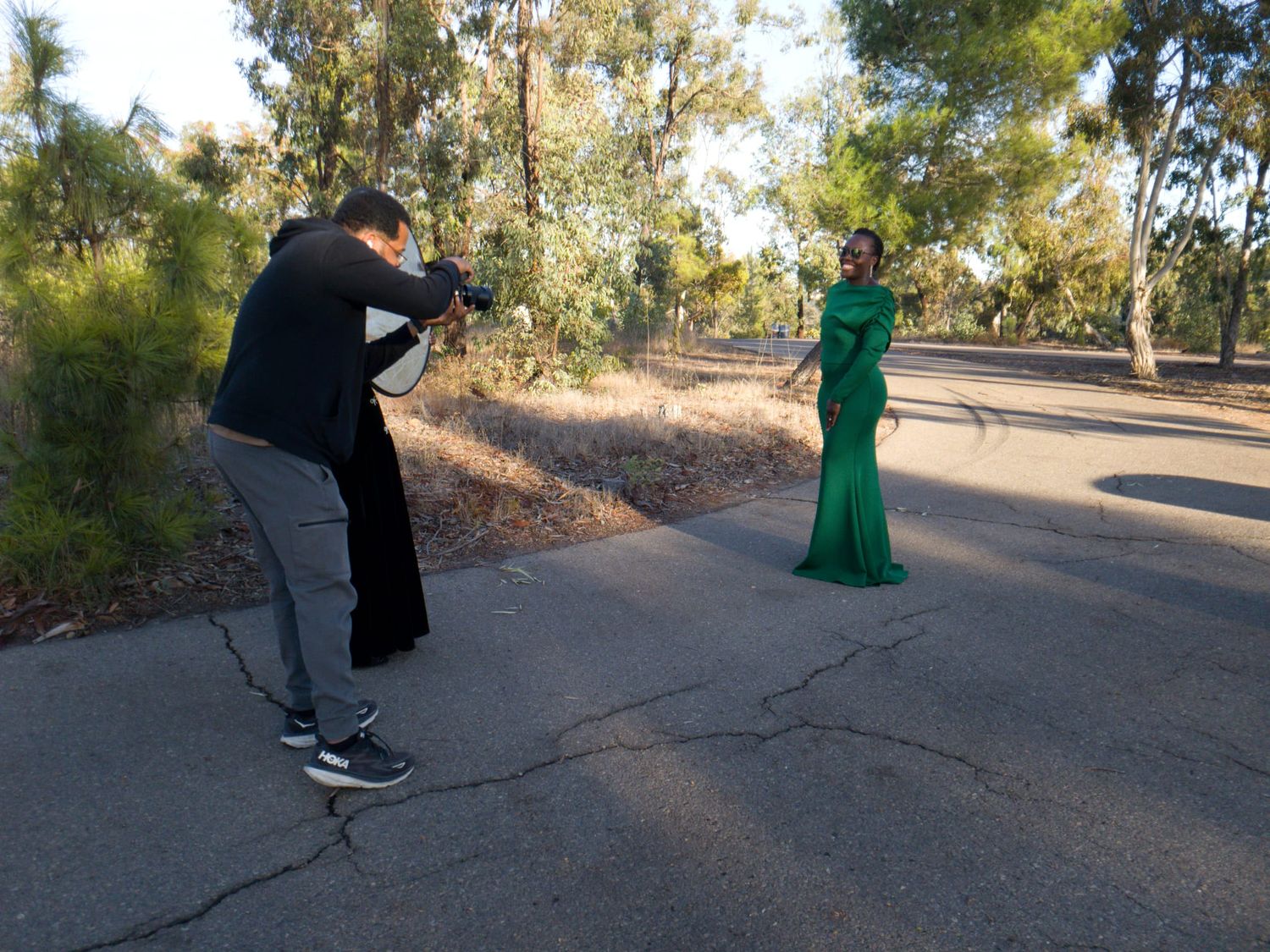 Behind the scenes of fashion photoshoot with photographer capturing model in emerald gown.