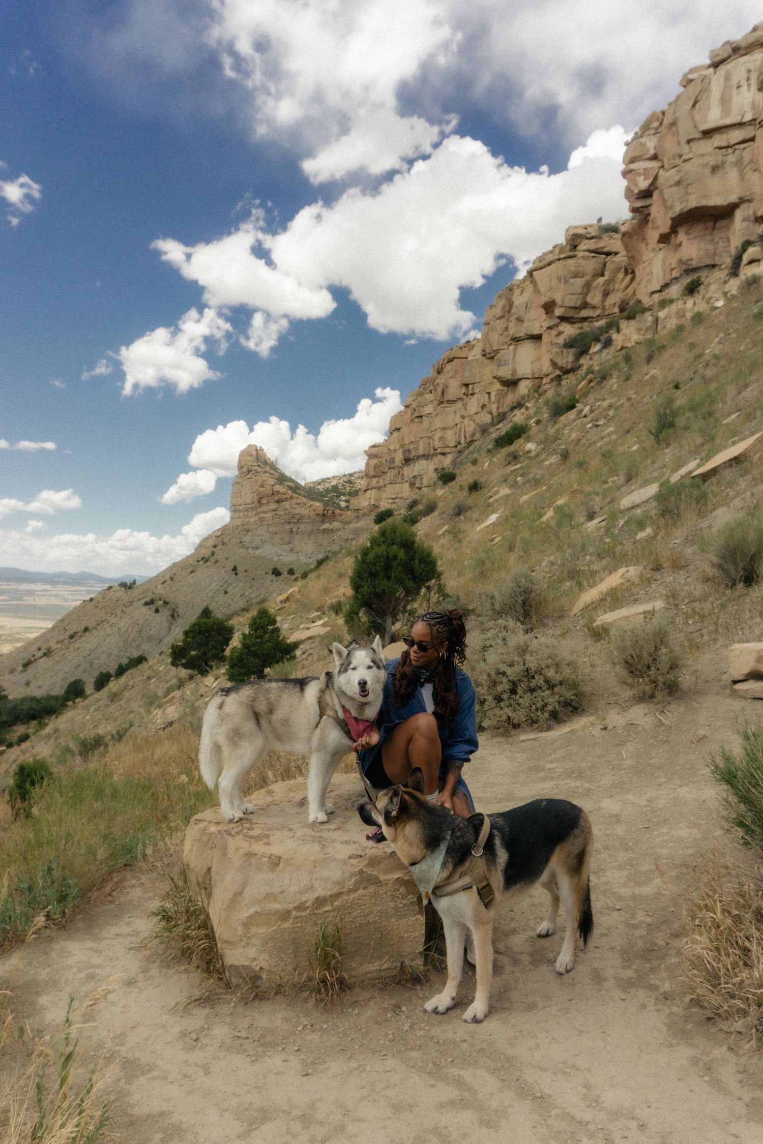 Scenic mountain hiking trail with people and horses navigating a rocky desert path beneath towering cliffs.