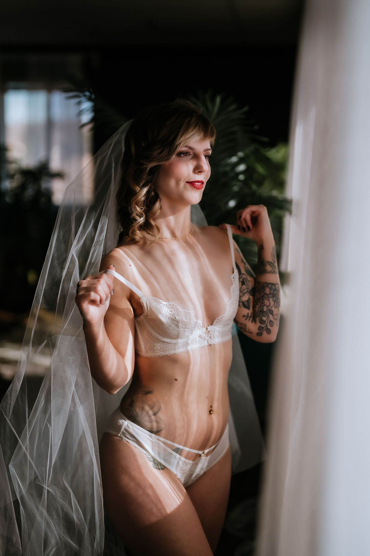 Dark and moody boudoir photography featuring lingerie, veil and natural window lighting.