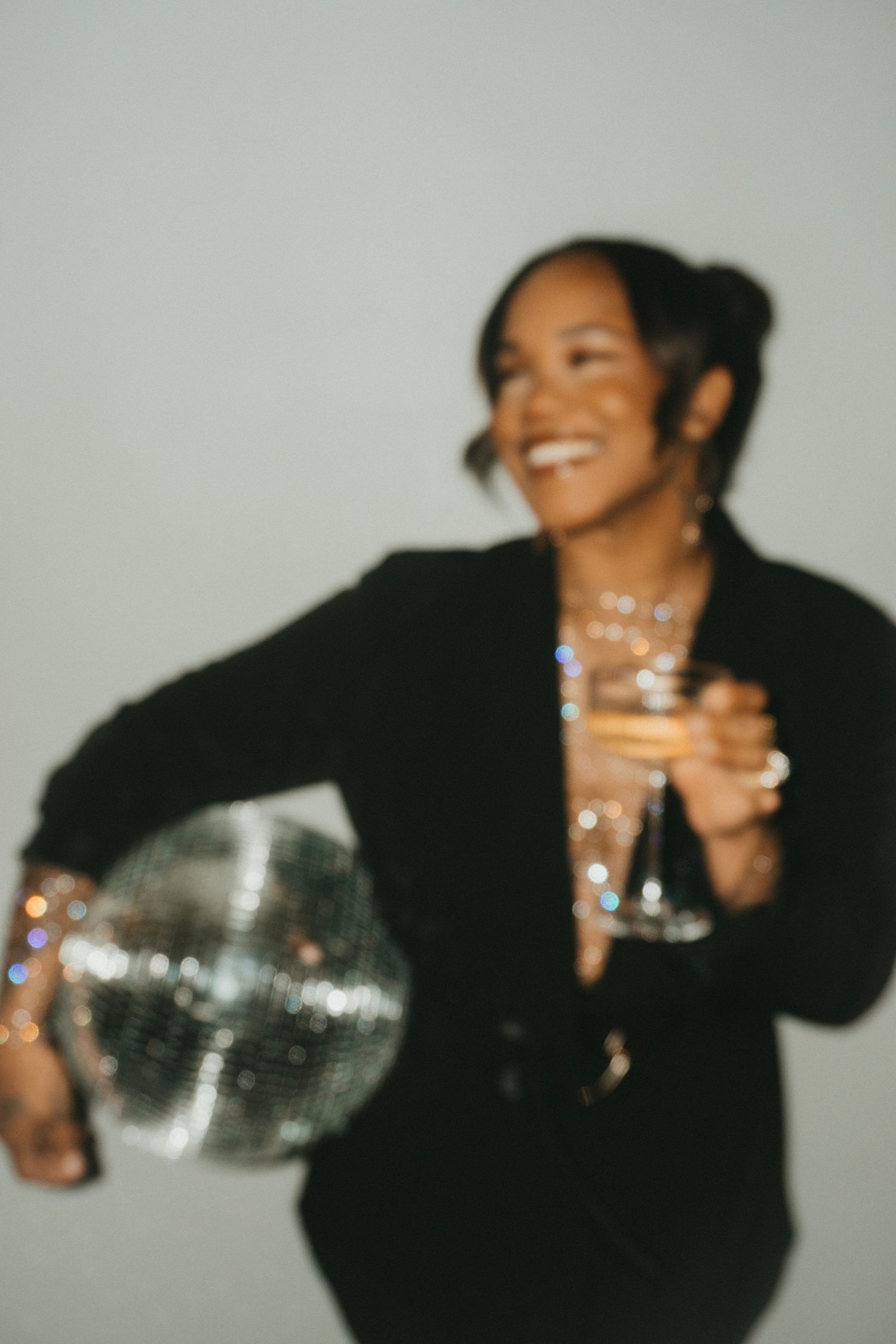A sequence of blurred photos showing someone in black clothing holding a glass and laughing.