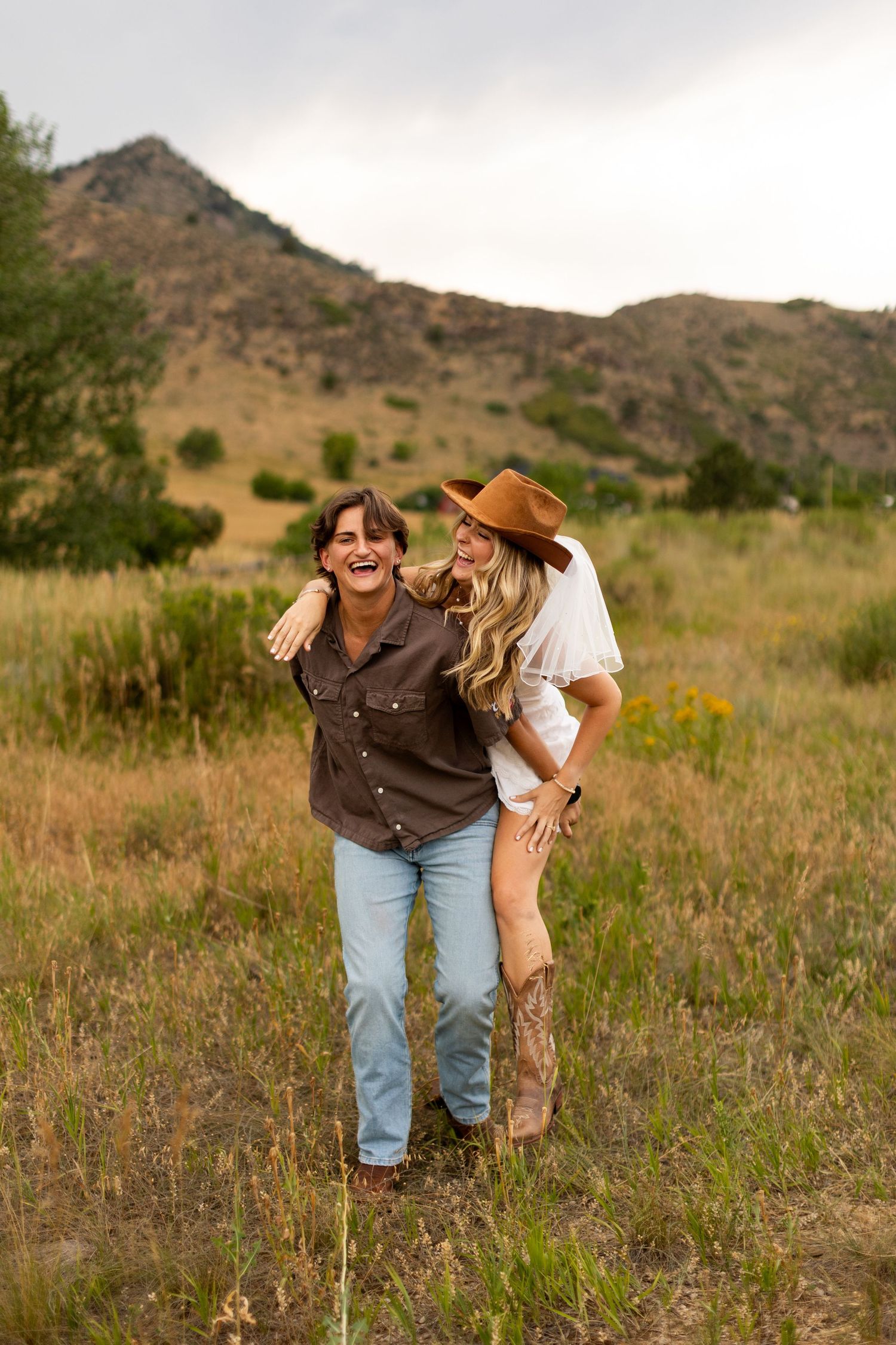 Couple shares joyful moments in a mountain meadow during golden hour.