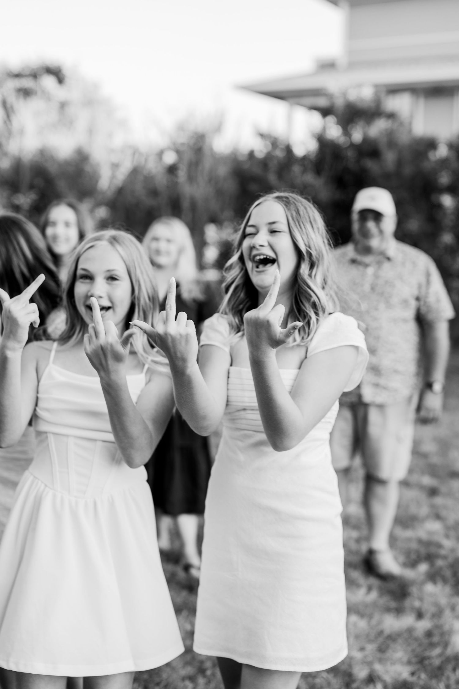 Children in white dresses laugh and play together outdoors.