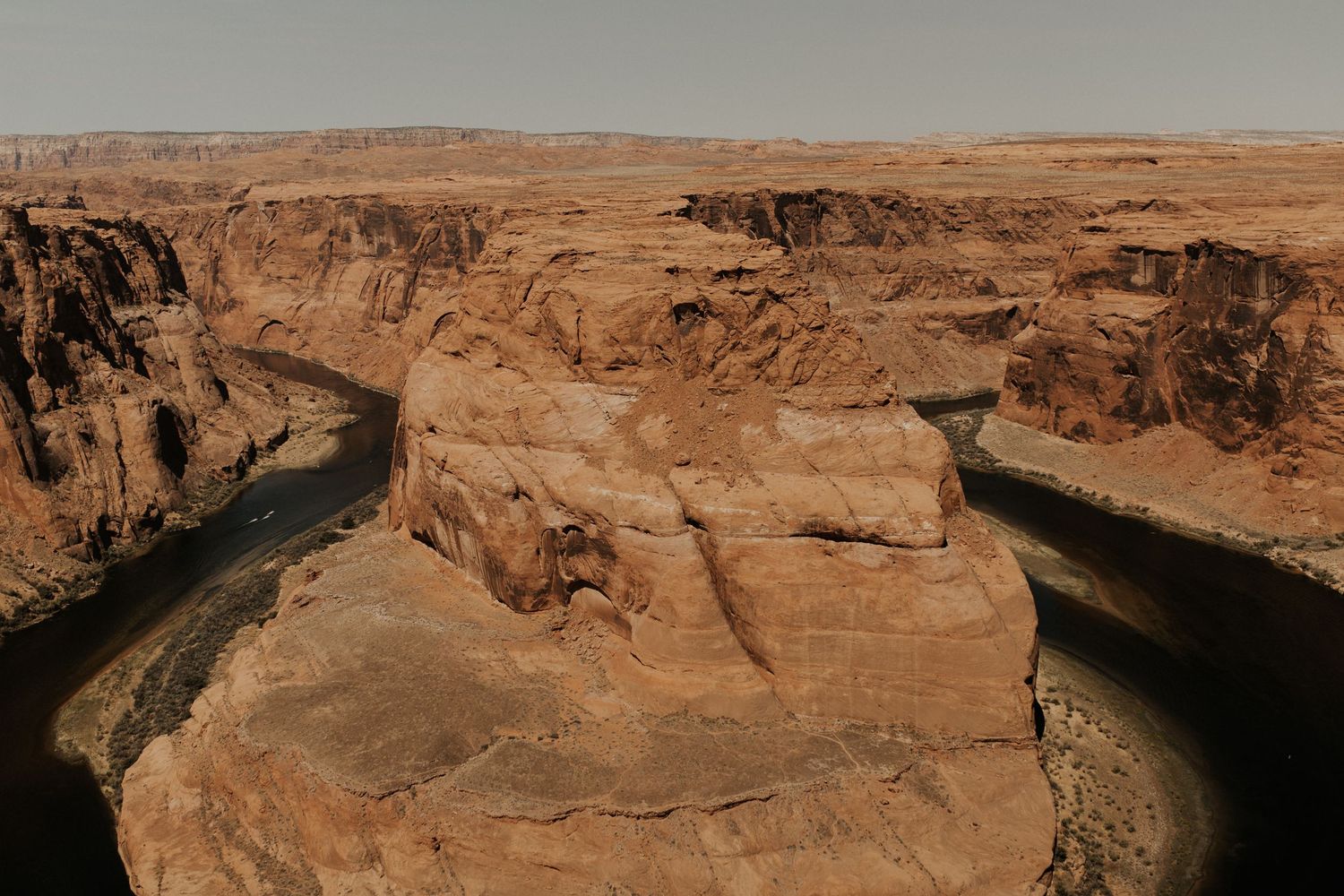 Aerial view of Horseshoe Bend canyon with the Colorado River curving around red sandstone rock formations.