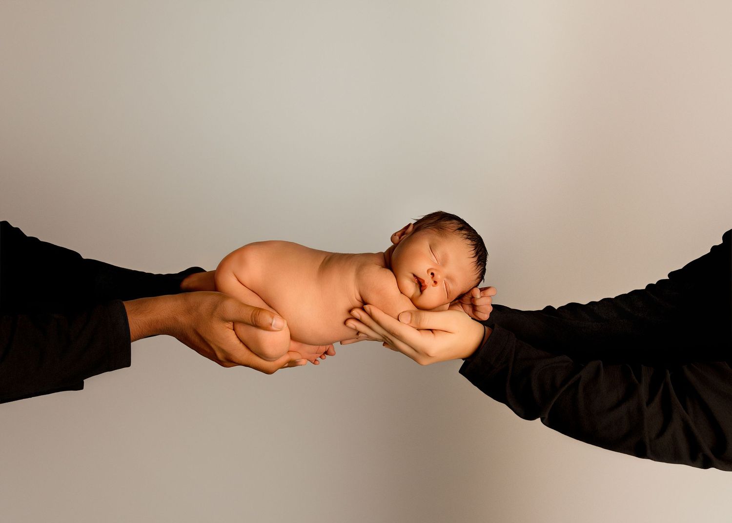 Bum up in mom and dad's arms during an in-studio newborn photography session in Peoria IL studio