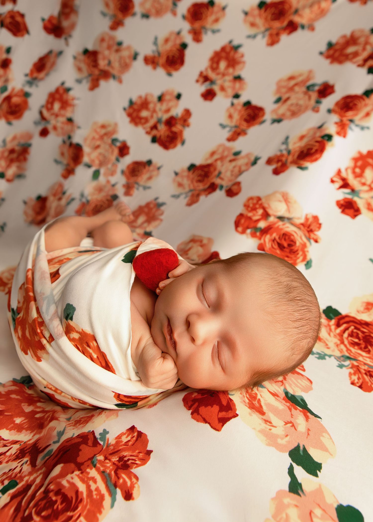 Newborn girl photoshoot in Peoria Illinois with flowered backdrop and heart lovie