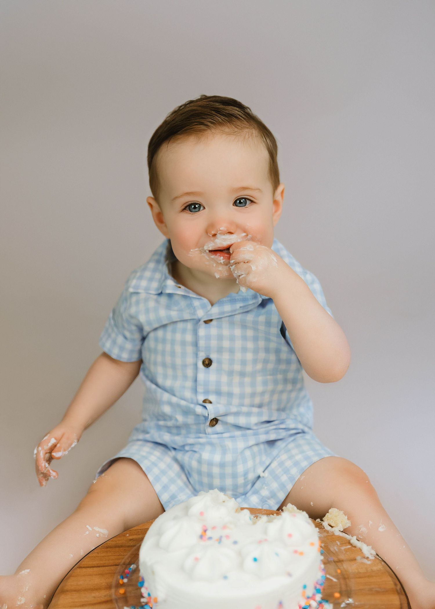 Cake Smash photography session for baby boy while smiling and eating cake