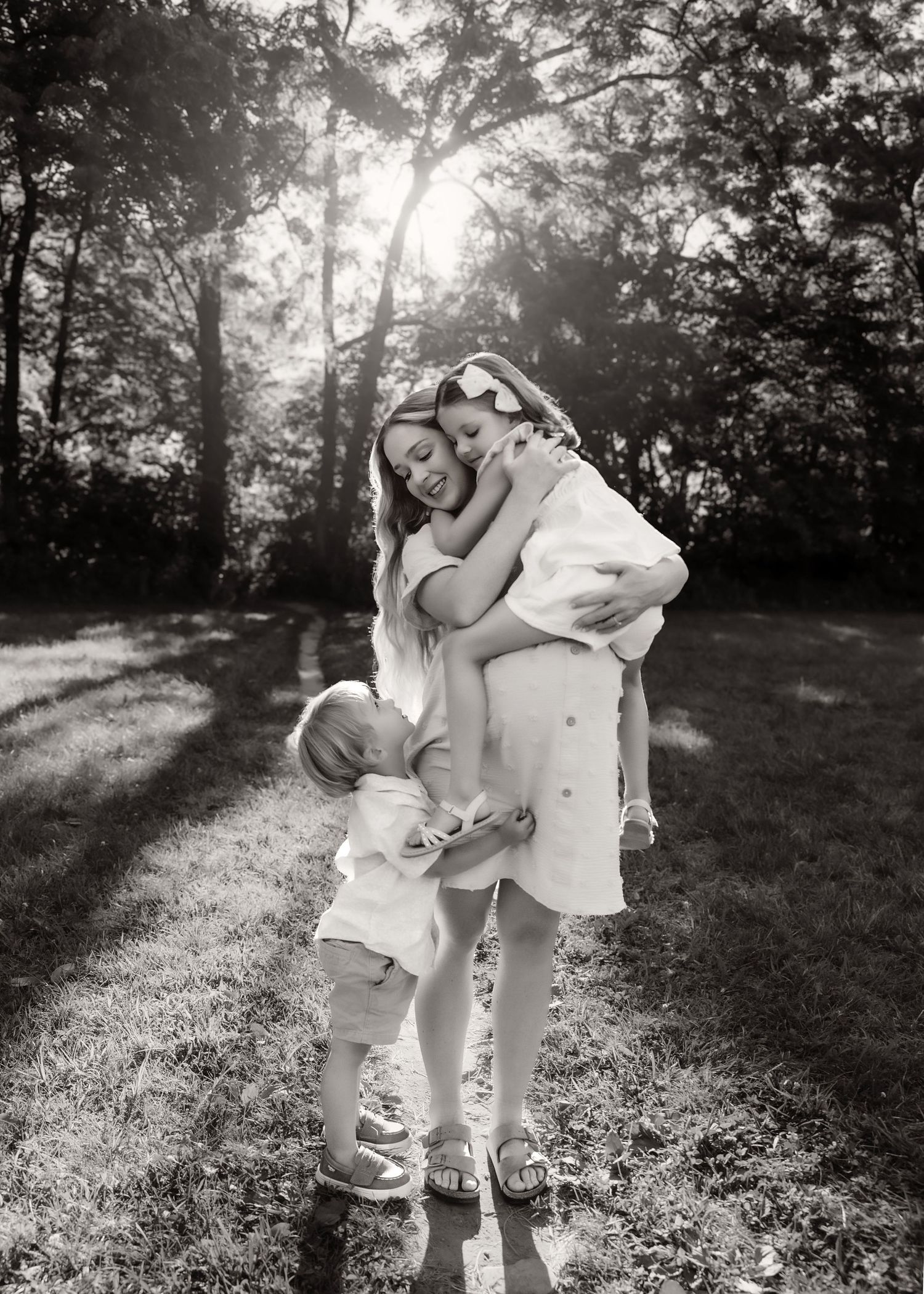 Black and white family maternity session during sunset, mom snuggling her two babies with a third on the way