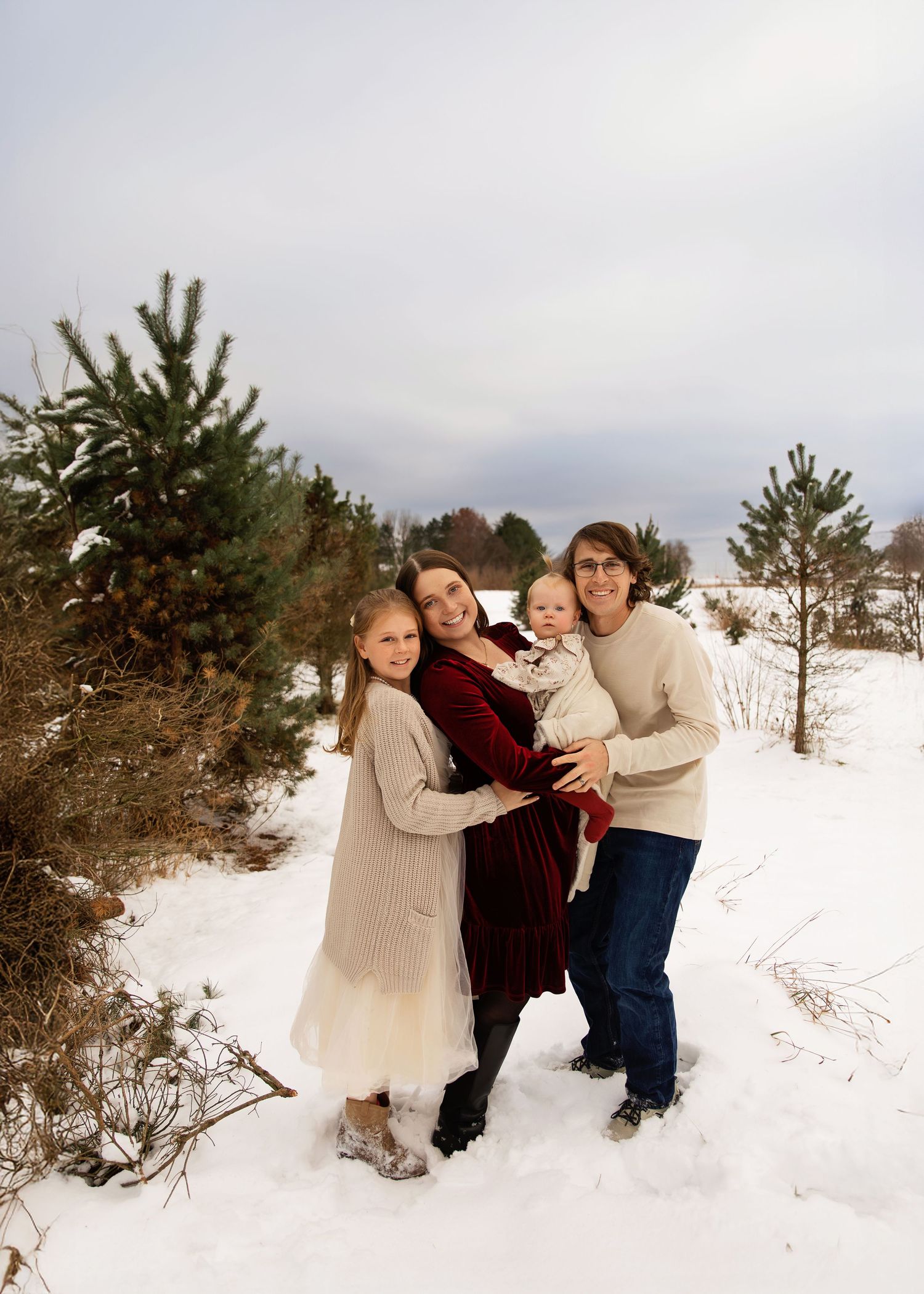 Winter family session of family of 4 with snow at a Christmas tree farm in Chillicothe Illinois