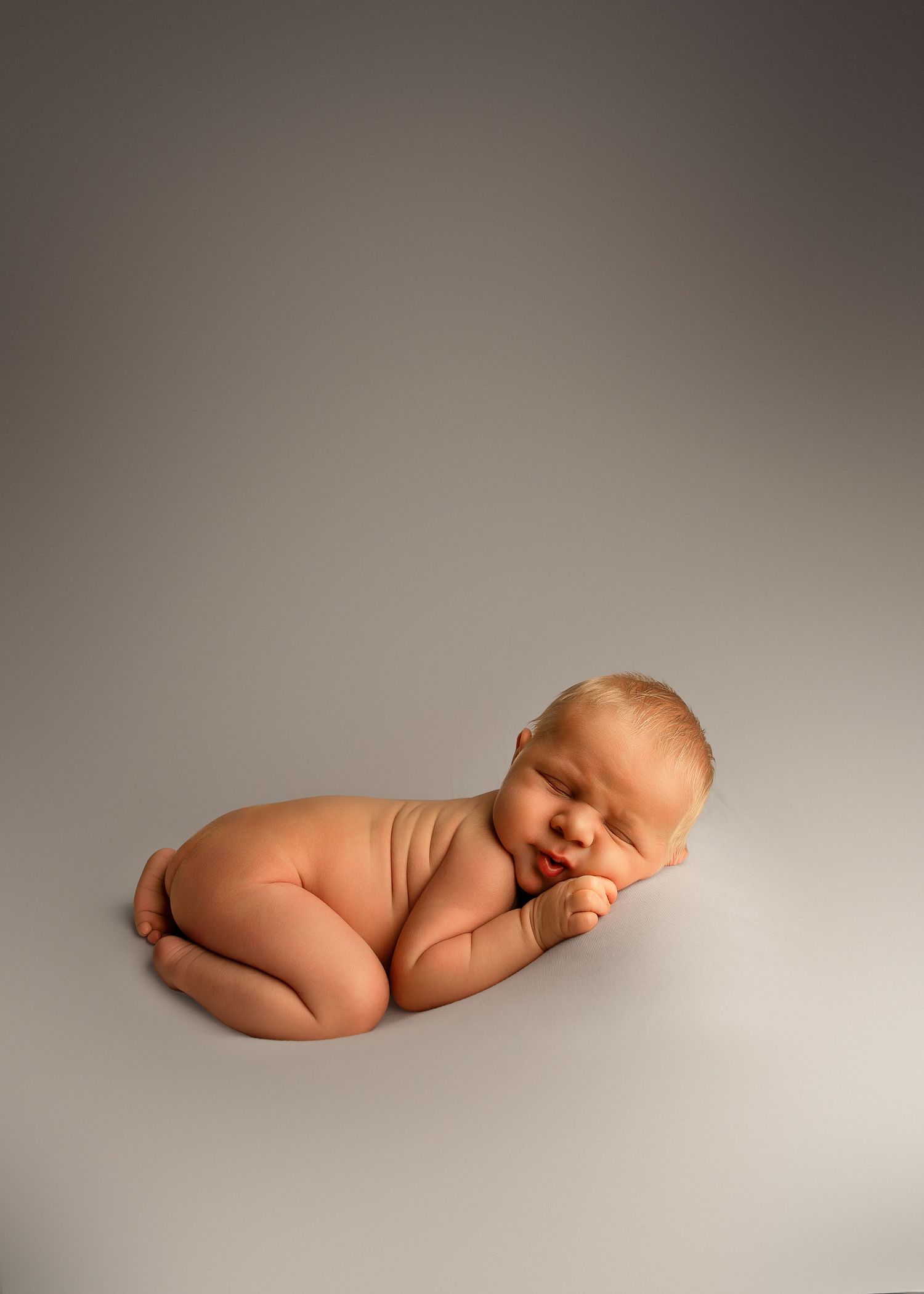 Bum up posed newborn session in Peoria IL on white backdrop and baby boy rolls