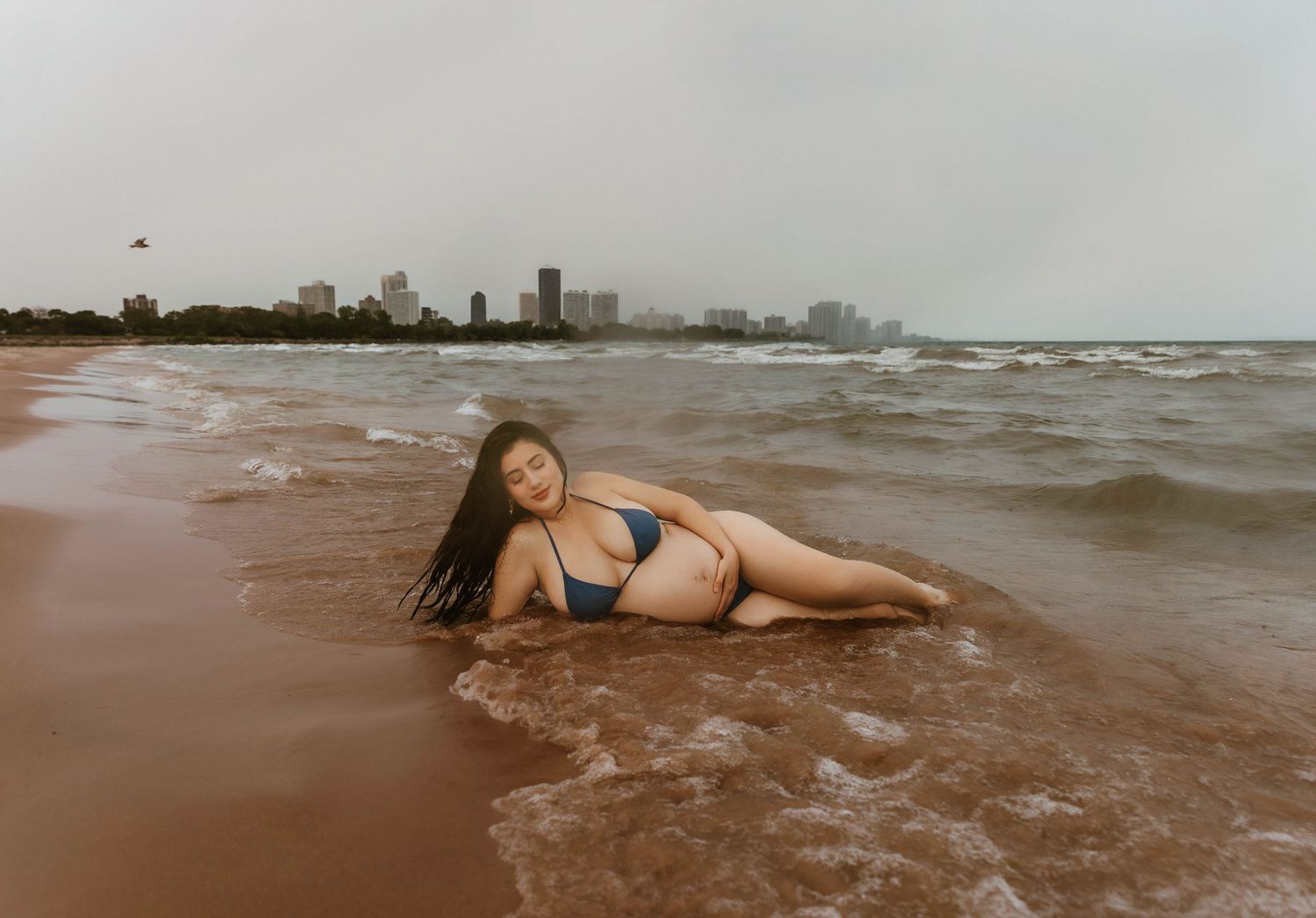 Beach Swim maternity session on overcast day on Montrose Beach in Chicago, IL