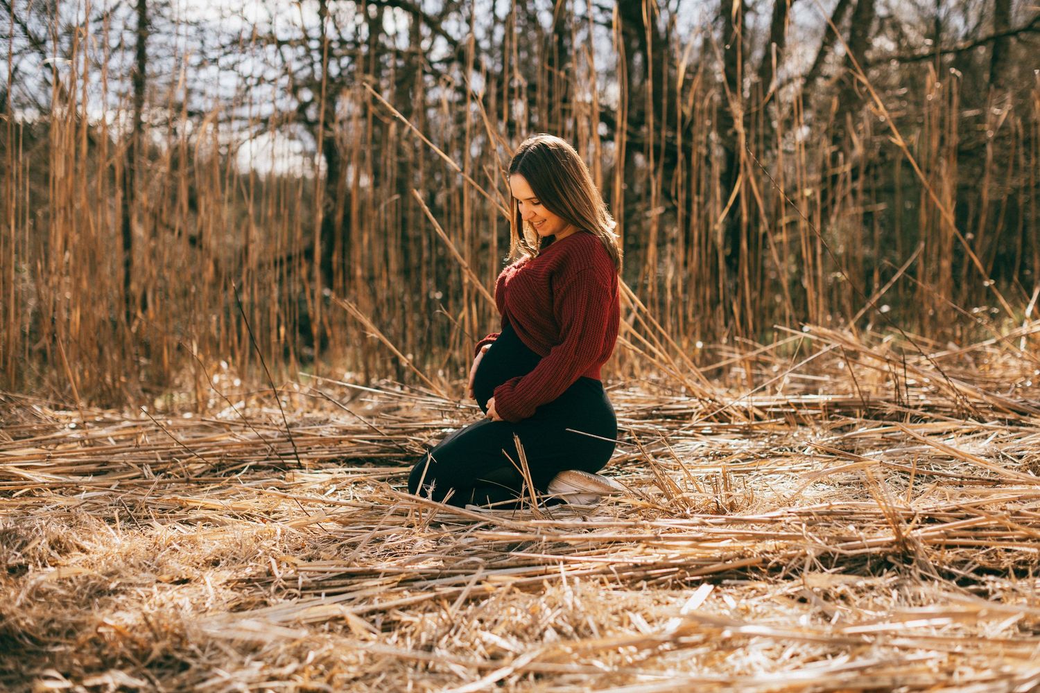 A serene maternity moment captured in a field of dry autumn grass.