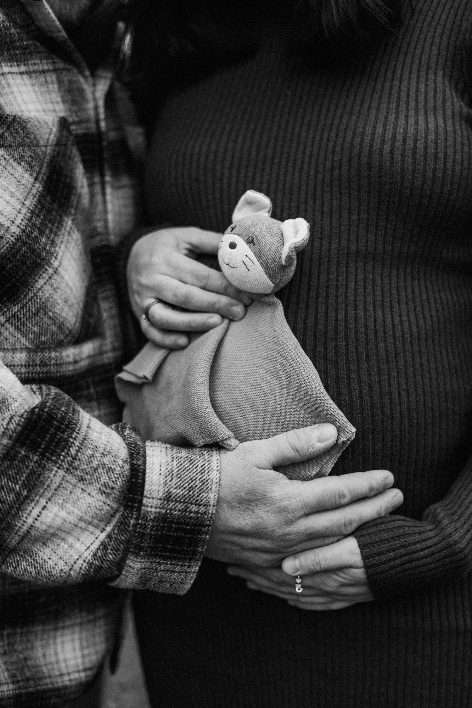 Black and white close-up of hands holding a small plush toy animal.