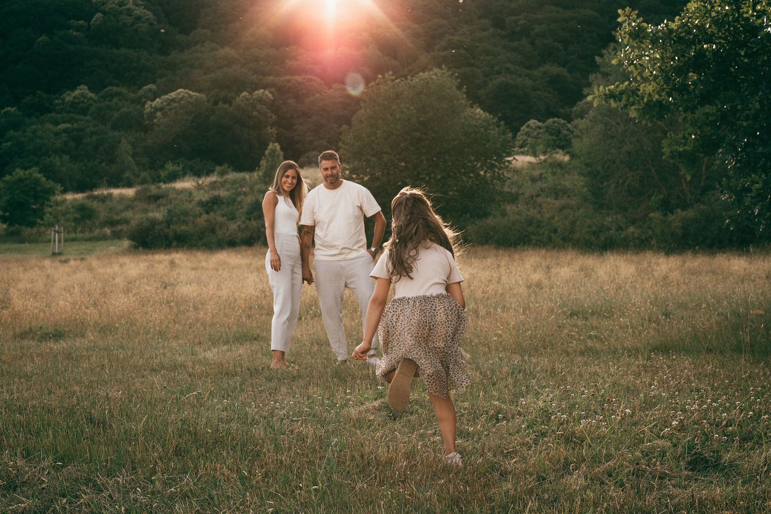 Familie spielt gemeinsam in einer goldenen Wiese beim Sonnenuntergang