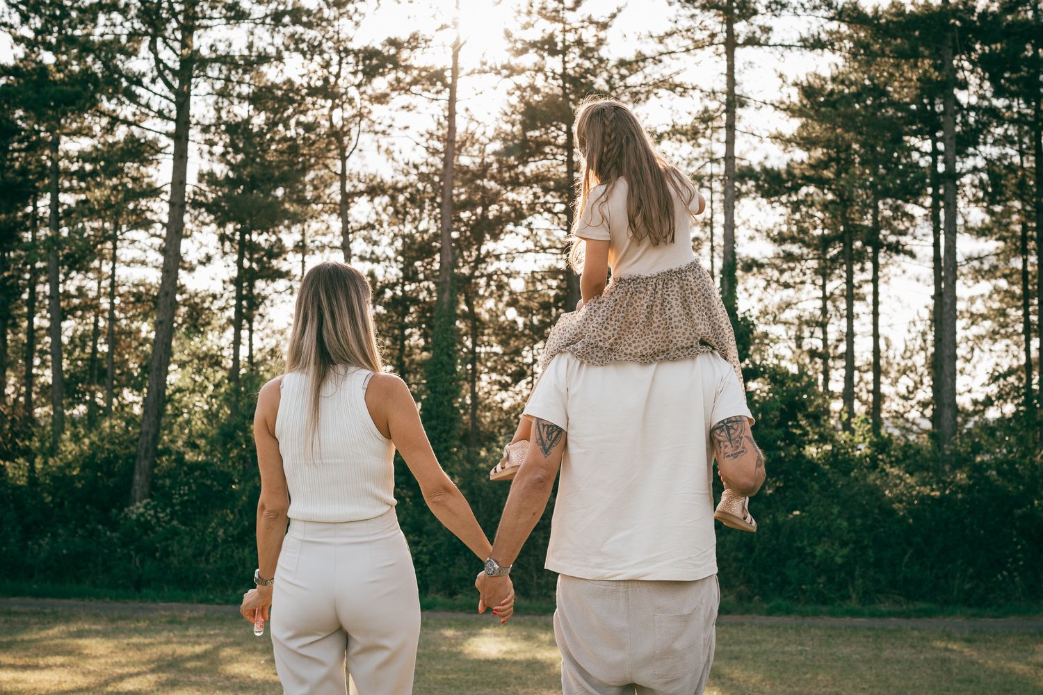 Eine Familie spaziert gemeinsam durch einen Kiefernwald im Licht der goldenen Stunde.