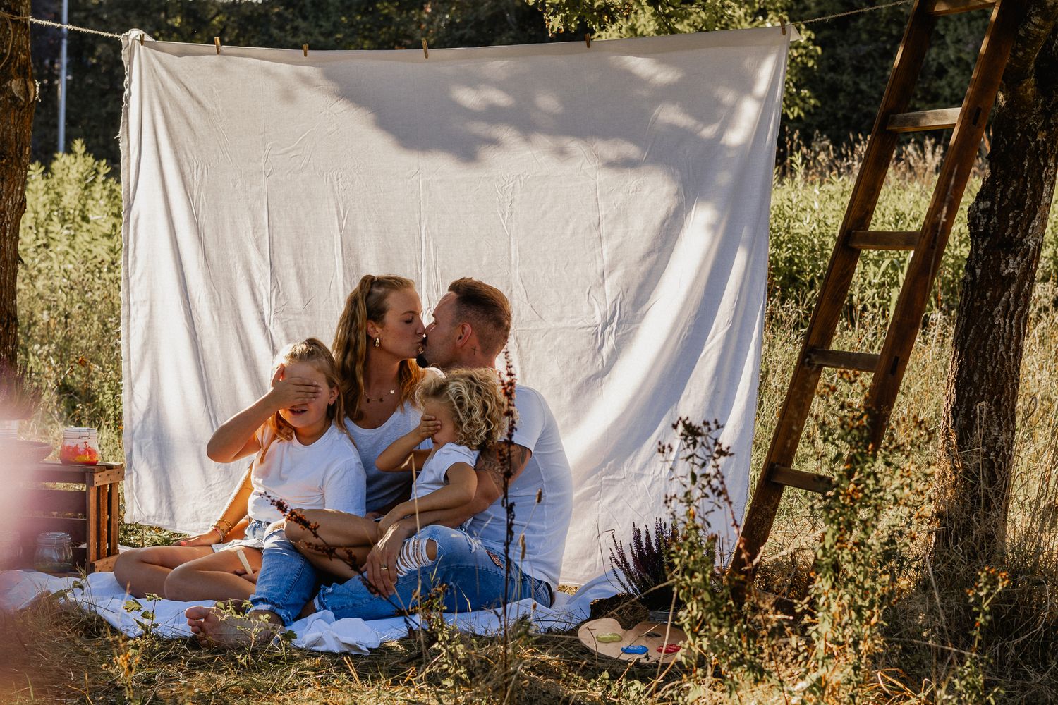 Eine authentische Familie, die sich fröhlich in einem sonnendurchfluteten Grasfeld vergnügt in Konz.