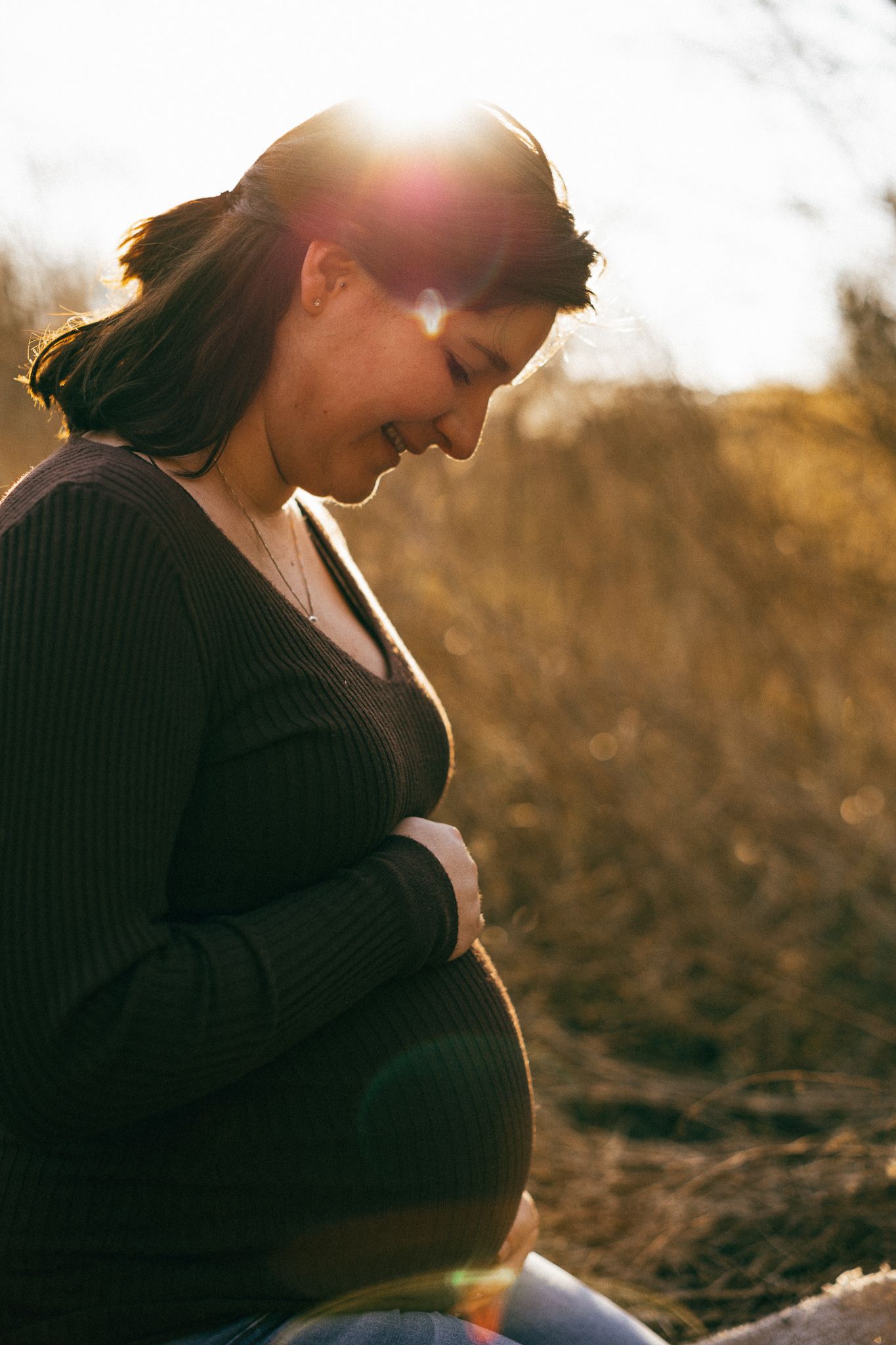 Silhouette des Babybauchs einer schwangeren Frau, vom goldenen Sonnenlicht in der Natur hinterleuchtet in Konz.
