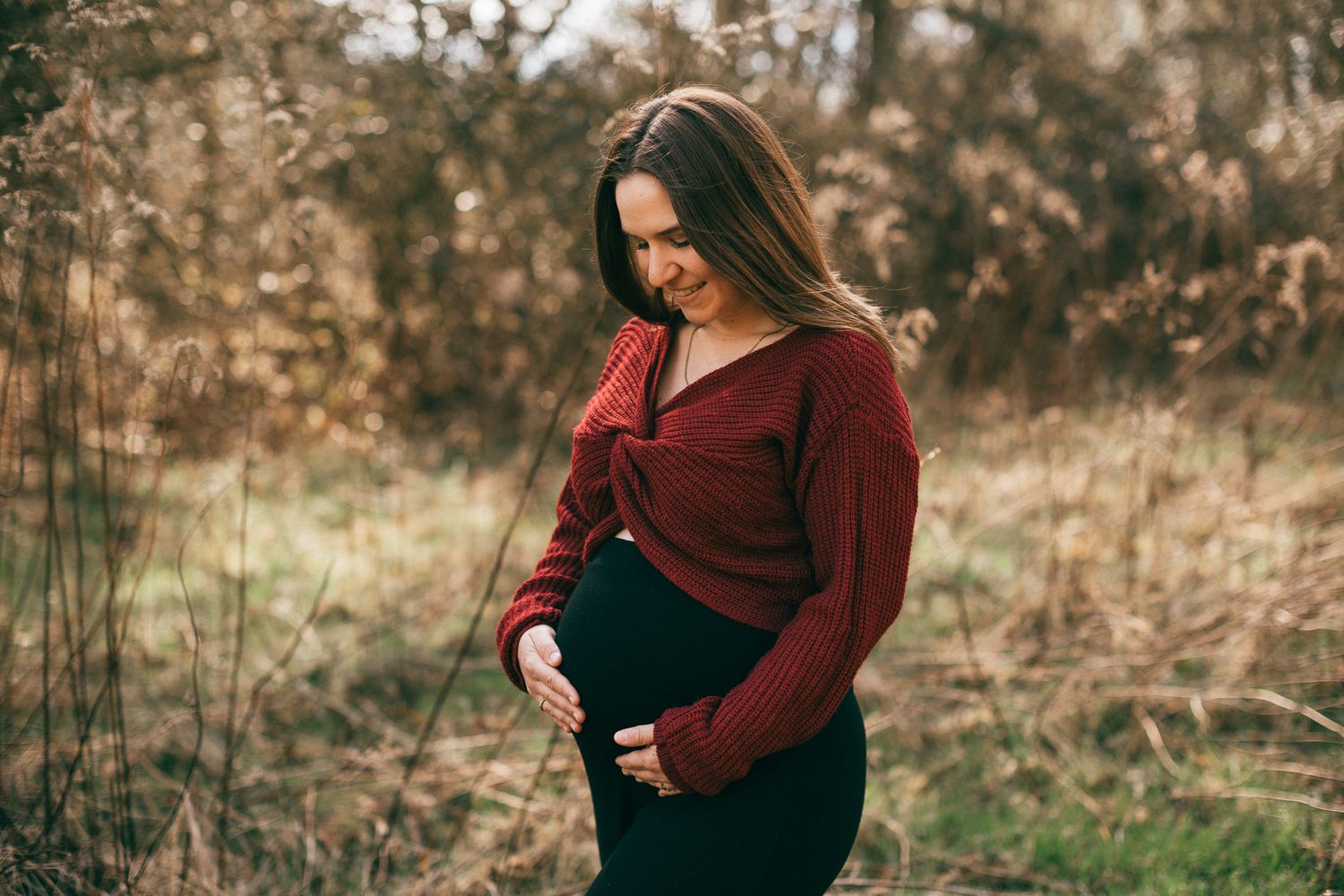 Eine werdende Mamam genießt das Shooting und umarmt liebevoll ihren Babybauch in Konz.
