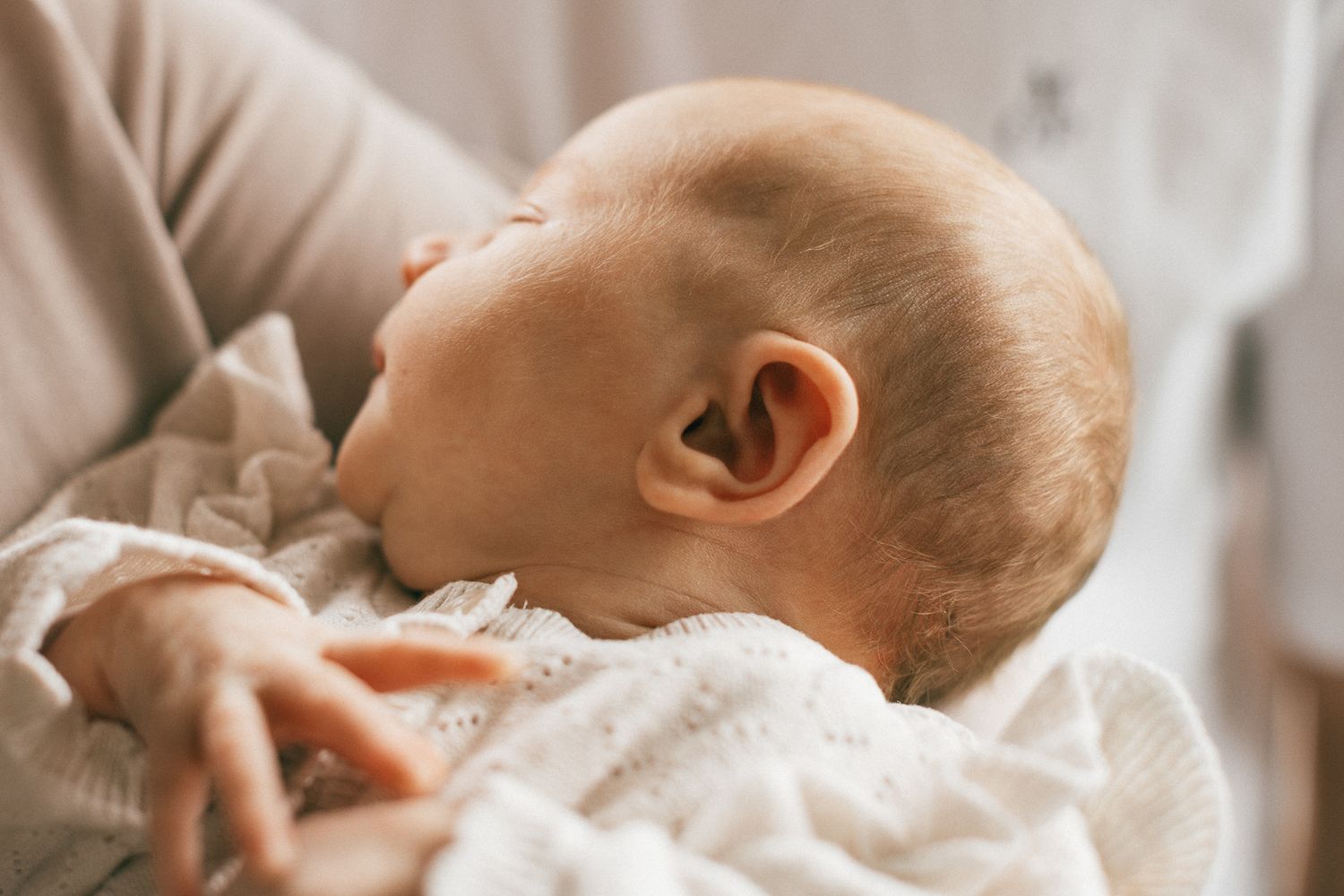 Ein Baby, behutsam in eine weiche weiße Decke gehüllt, liegt entspannt auf einer flauschigen Unterlage in seinem Zuhause in Trier