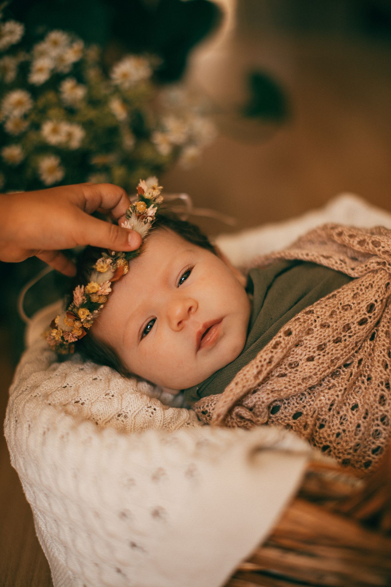 Ein süßes Baby ruht auf weißem, strukturiertem Stoff, während Blumen darüber gelegt werden
