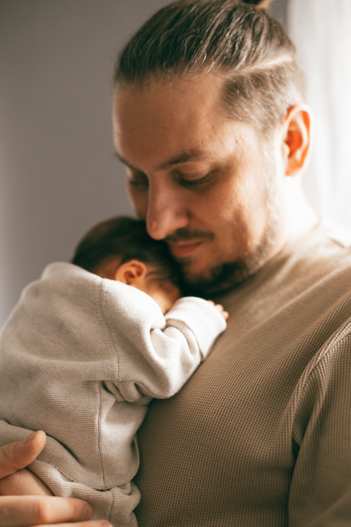 Ein zärtlicher Moment zwischen Vater und Tochter, eingefangen im weichen natürlichen Fensterlicht.
