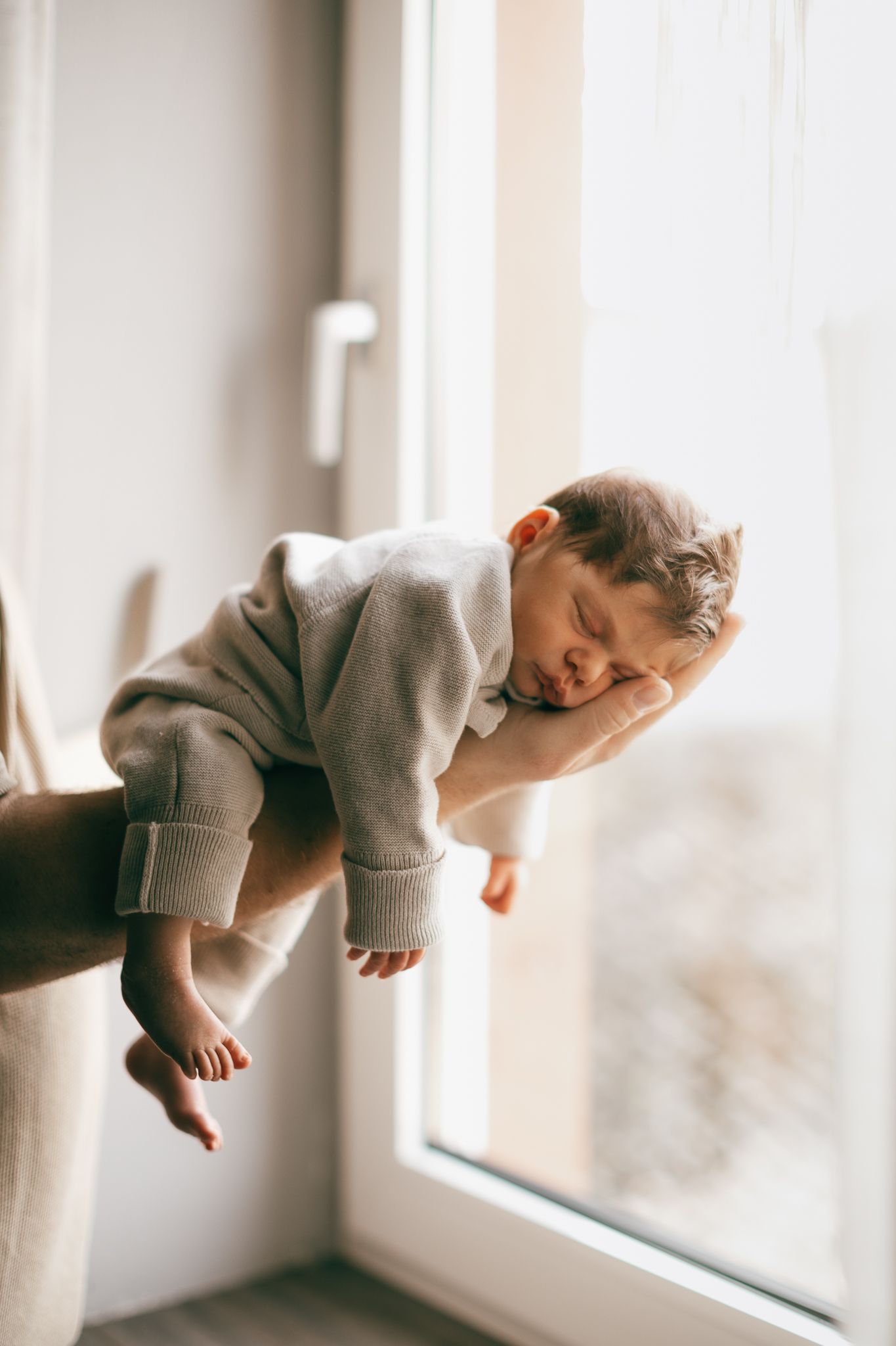 Eine künstlerische Fotoserie, die ein Baby im sanften natürlichen Licht am Fenster zeigt in Konz.