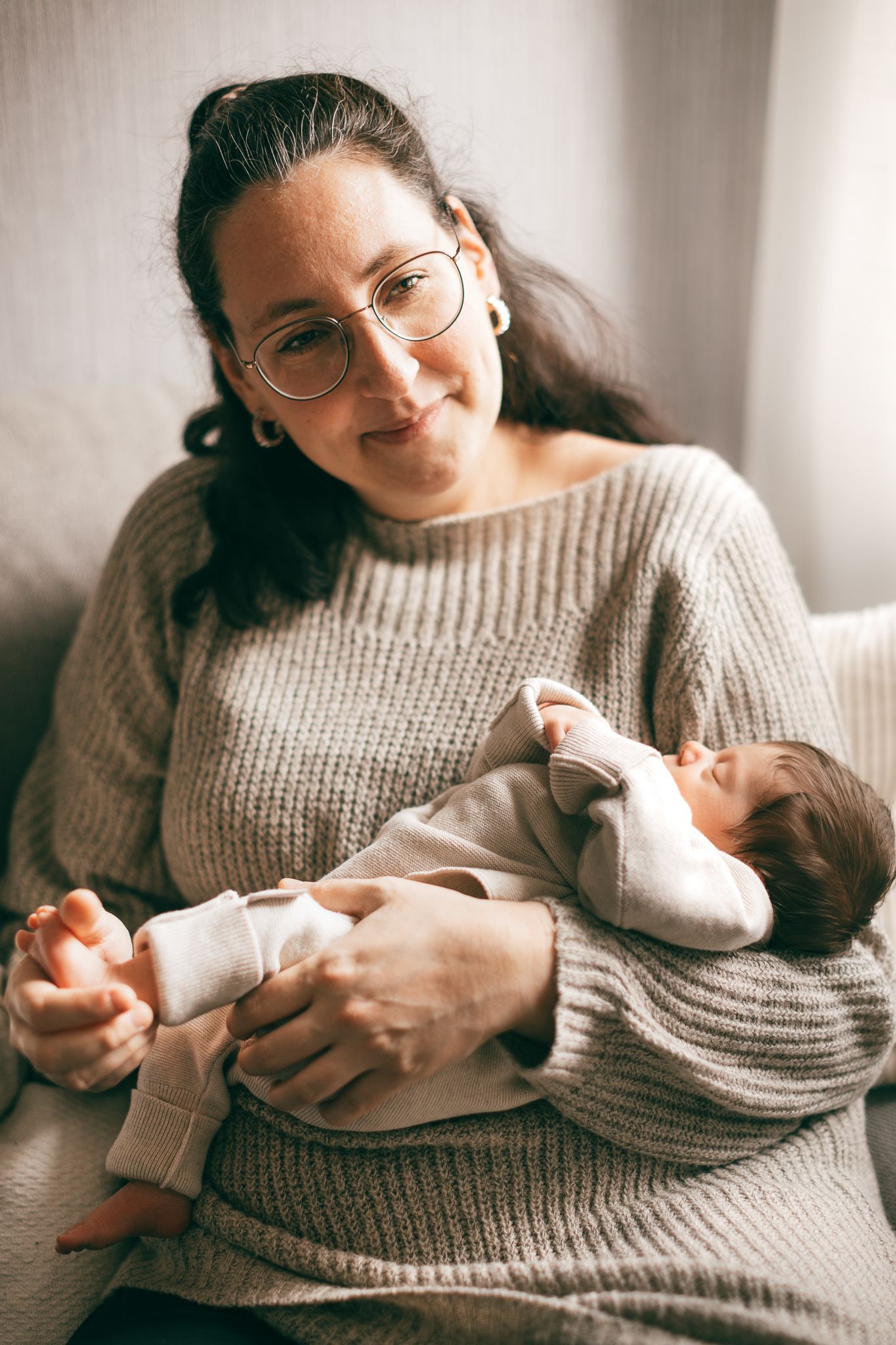 Eine gemütliche Szene, in der ein Baby in einem gestrickten Pullover behutsam gehalten wird in Konz.