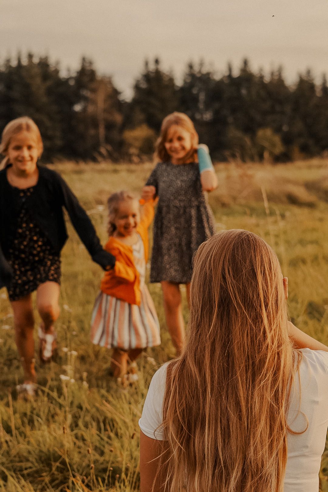 A group enjoys a carefree moment together in a grassy meadow at sunset.