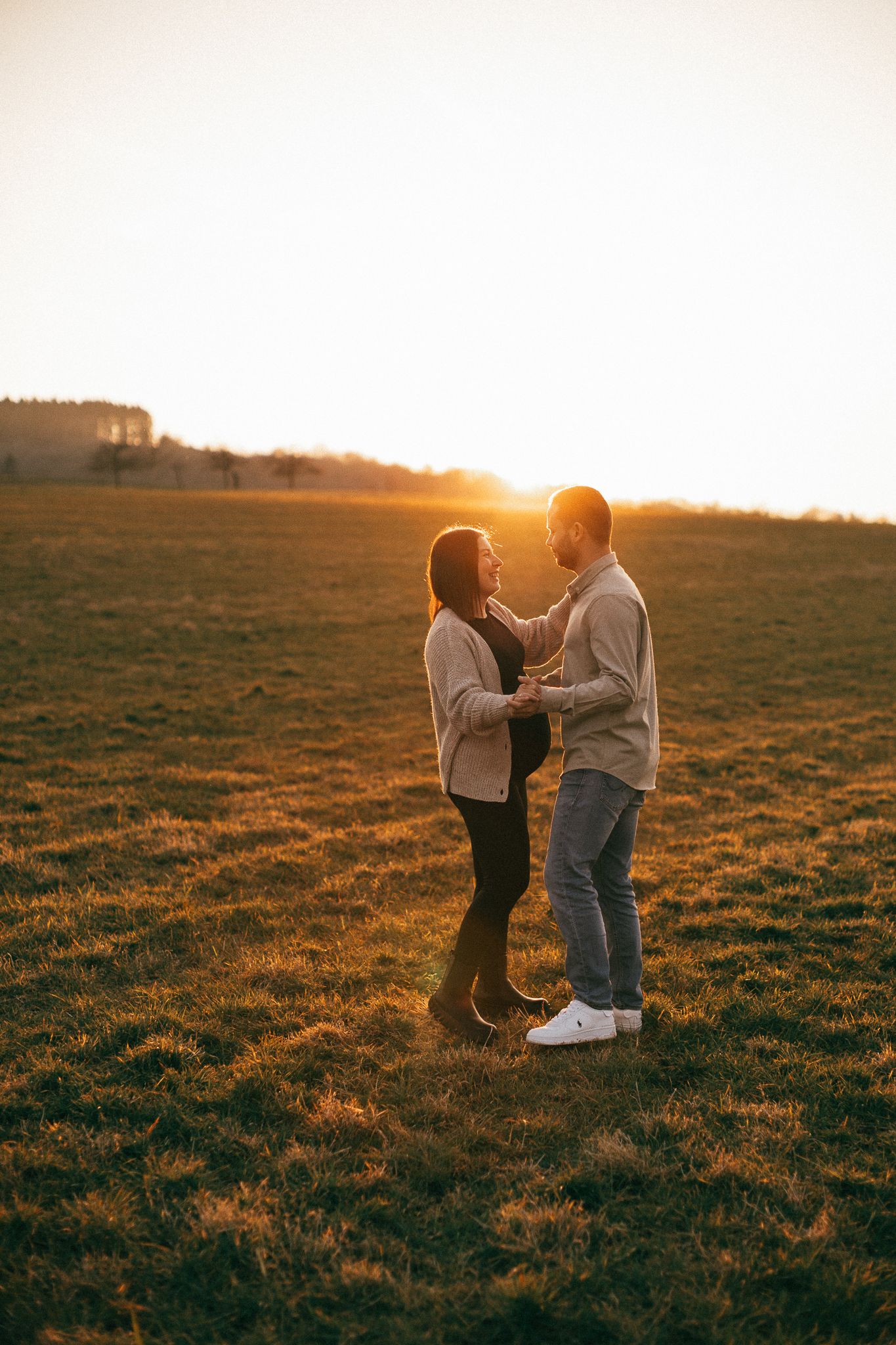 Fotoshooting zur Schwangerschaftsverkündung bei Sonnenuntergang in einer goldenen leuchtenden Wiese in Konz.