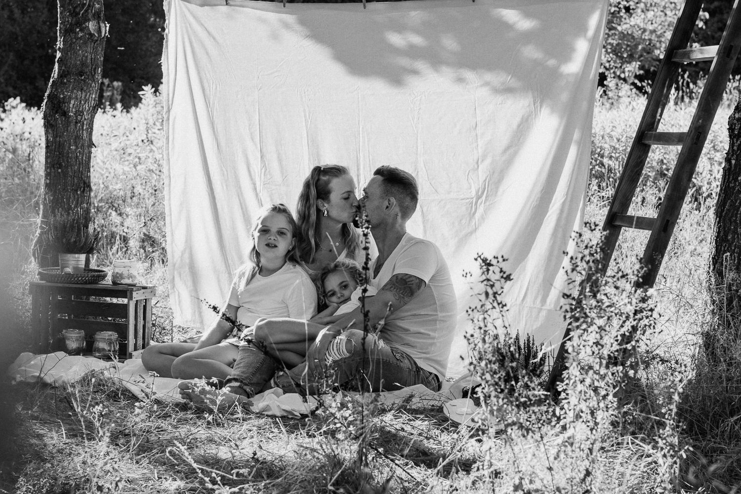 Familienfotosession unter freiem Himmel mit weißem Hintergrund, umgeben von Bäumen in Konz.