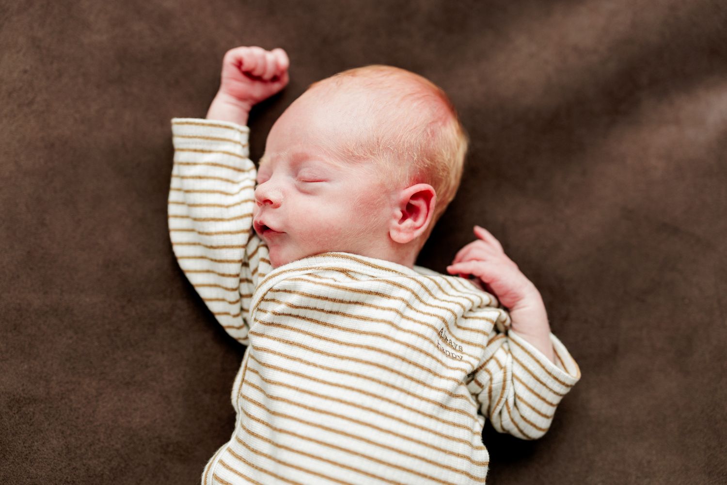 A newborn baby sleeping peacefully while wrapped in a striped blanket.