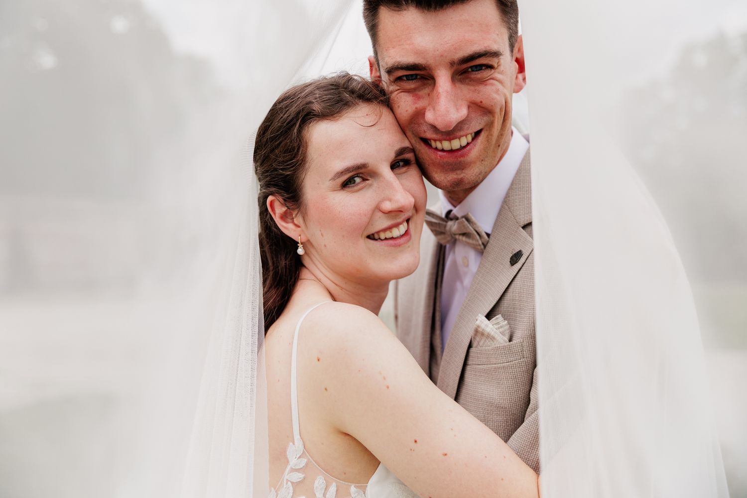A happy couple embracing and smiling on their wedding day.