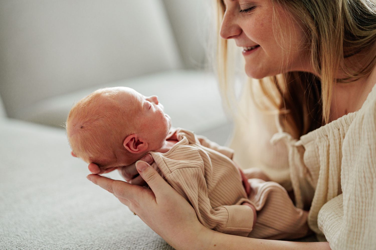 A mother gently holding and gazing at her newborn baby in her arms.