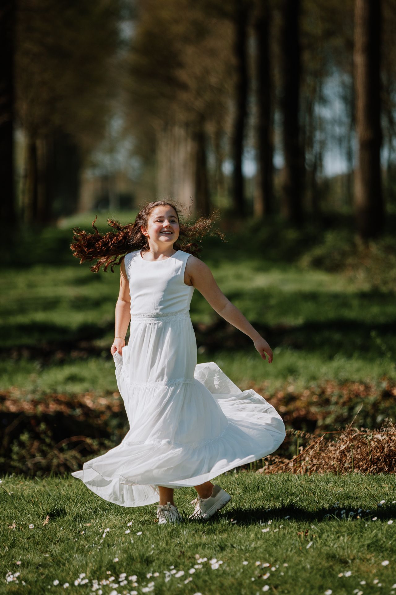 A woman in a white dress twirling and running through a lush, green forest.