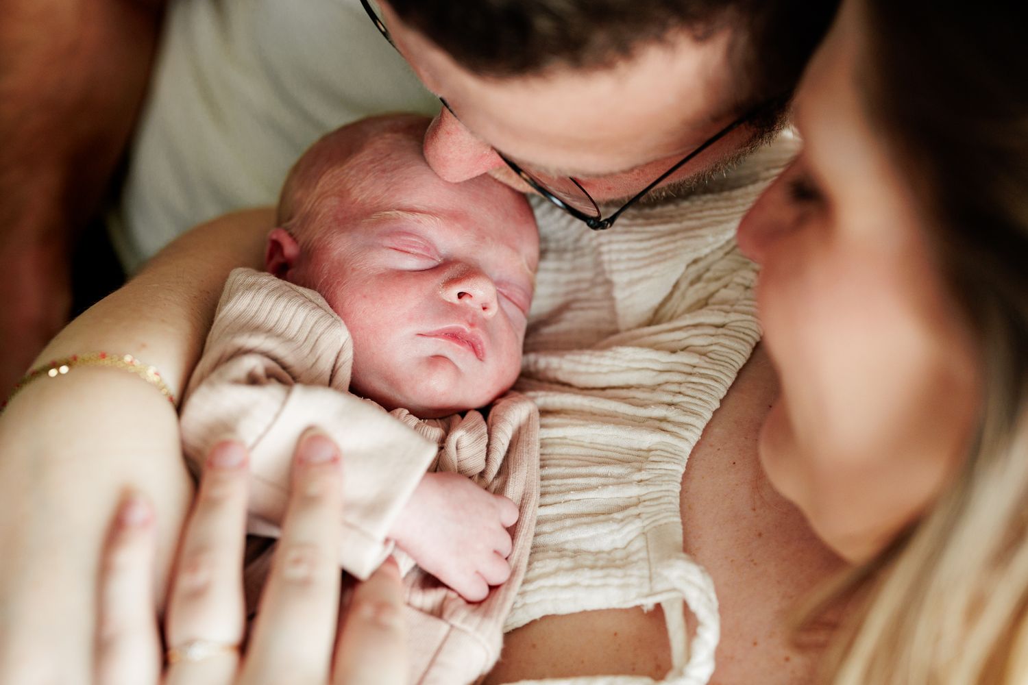 A man holds a newborn baby in his arms, displaying a tender and affectionate moment.