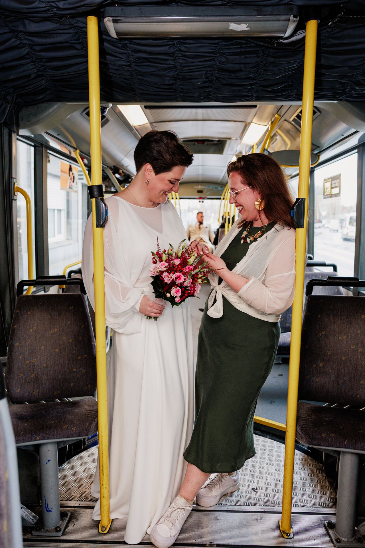 Bruid en bruidsmeisje staan samen op de bus en bekijken het bruidsboeket.