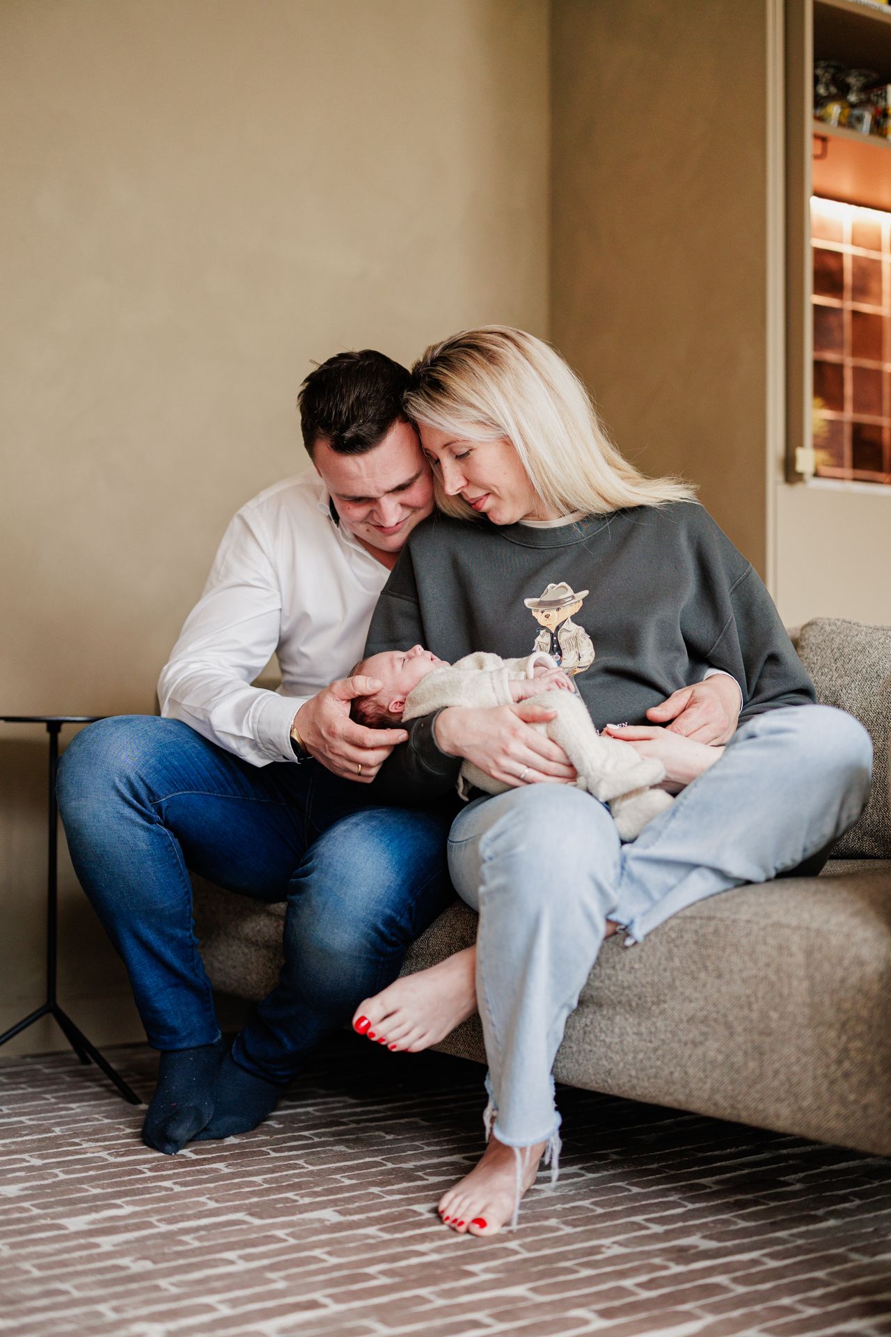 A couple sitting on a couch, the woman leaning against the man as they look at something together.