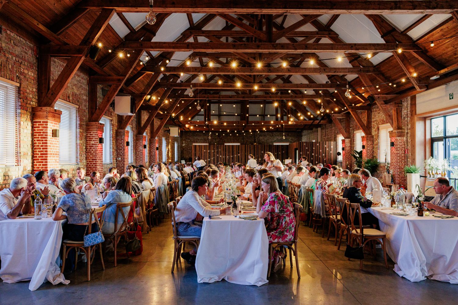 Grote, rustieke feestzaal met sfeerlichtjes en feesttafels in de Commanderie in Maldegem.