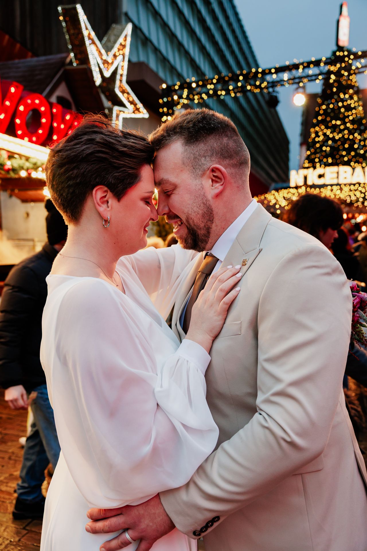 Koppel houdt elkaar vast op de kerstmarkt van Gent met lichtjes in de achtergrond
