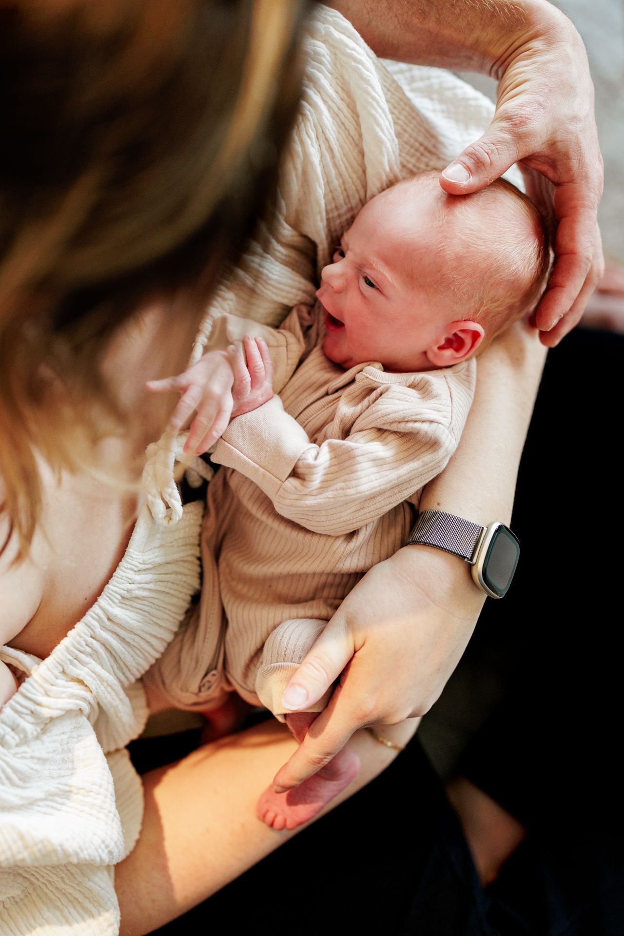 A woman gently cradles a sleeping newborn baby, with a look of love and care on her face.